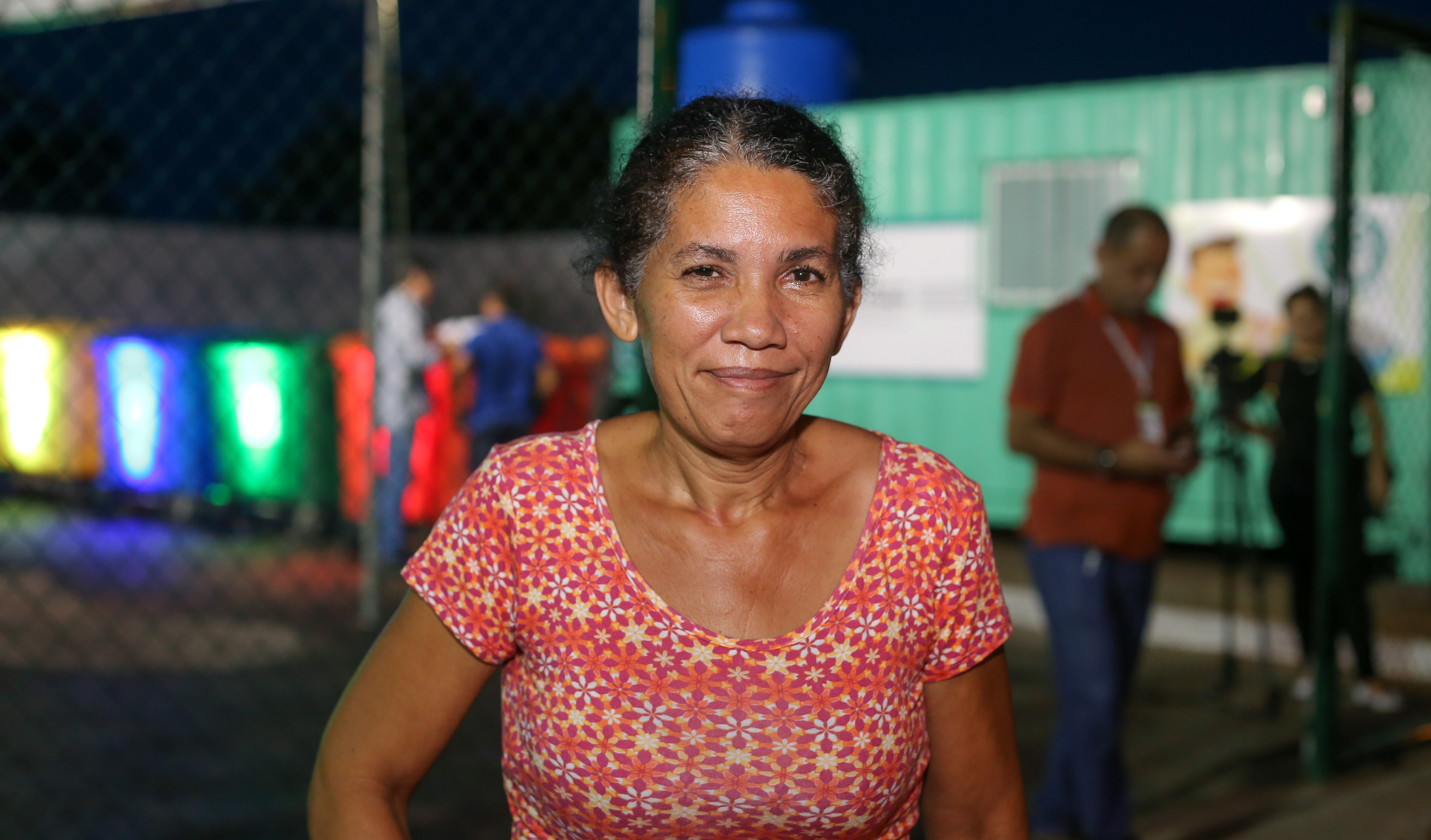 mulher com blusa vermelha florida posa para a foto sorrindo