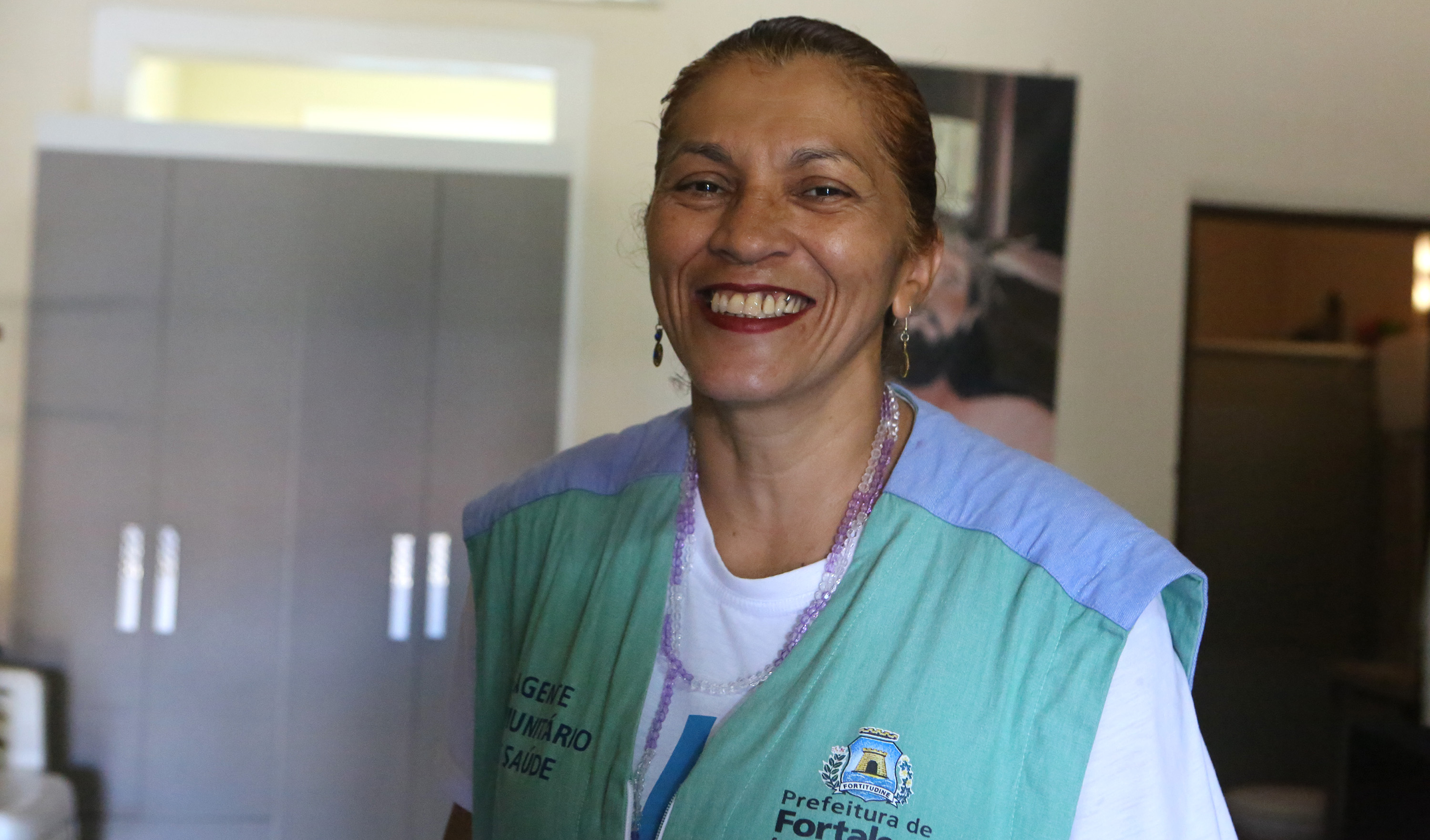 Mulher vestindo colete de agente de saúde e sorrindo