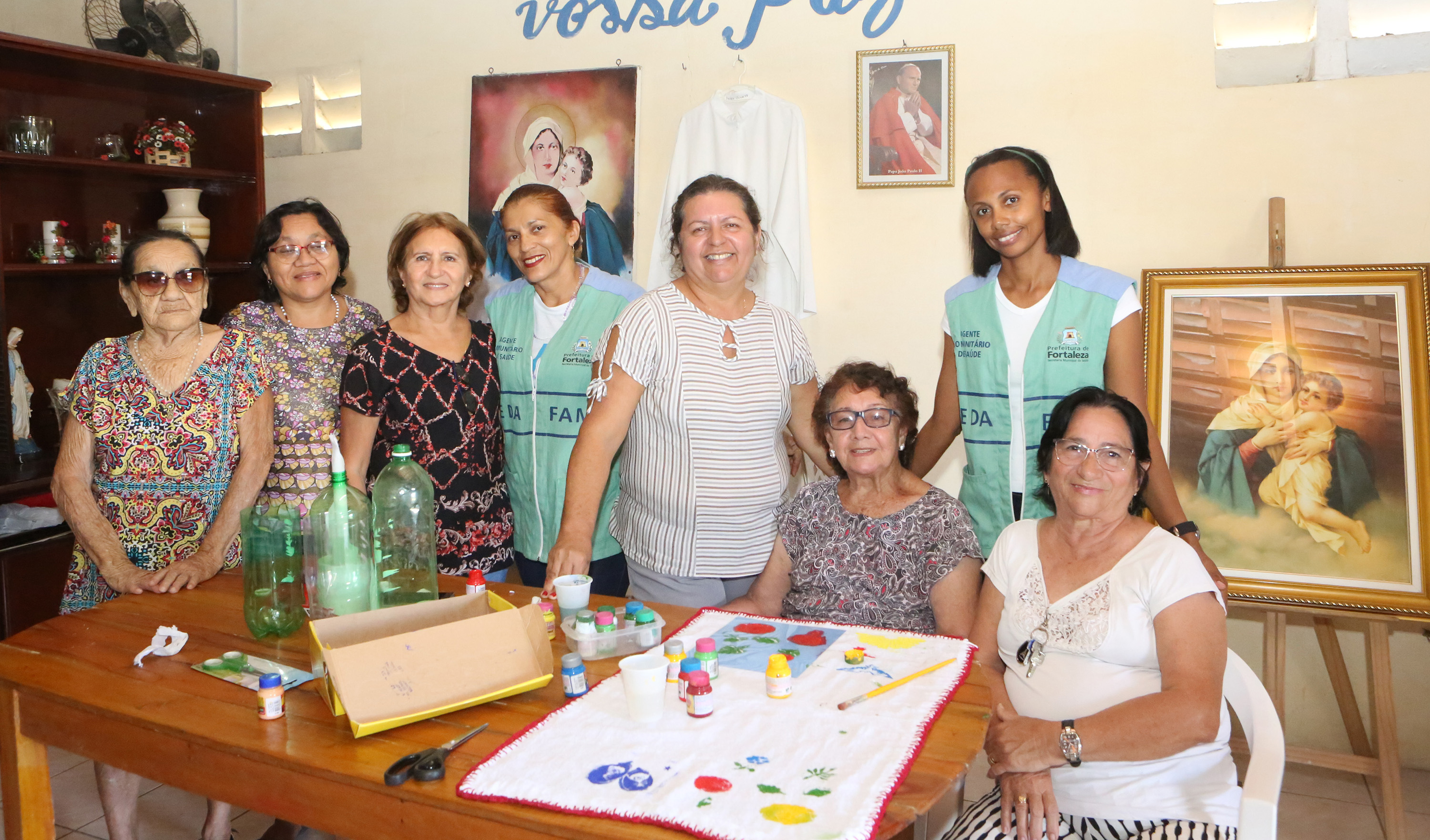 Senhoras reunidas ao redor de mesa com artesanatos