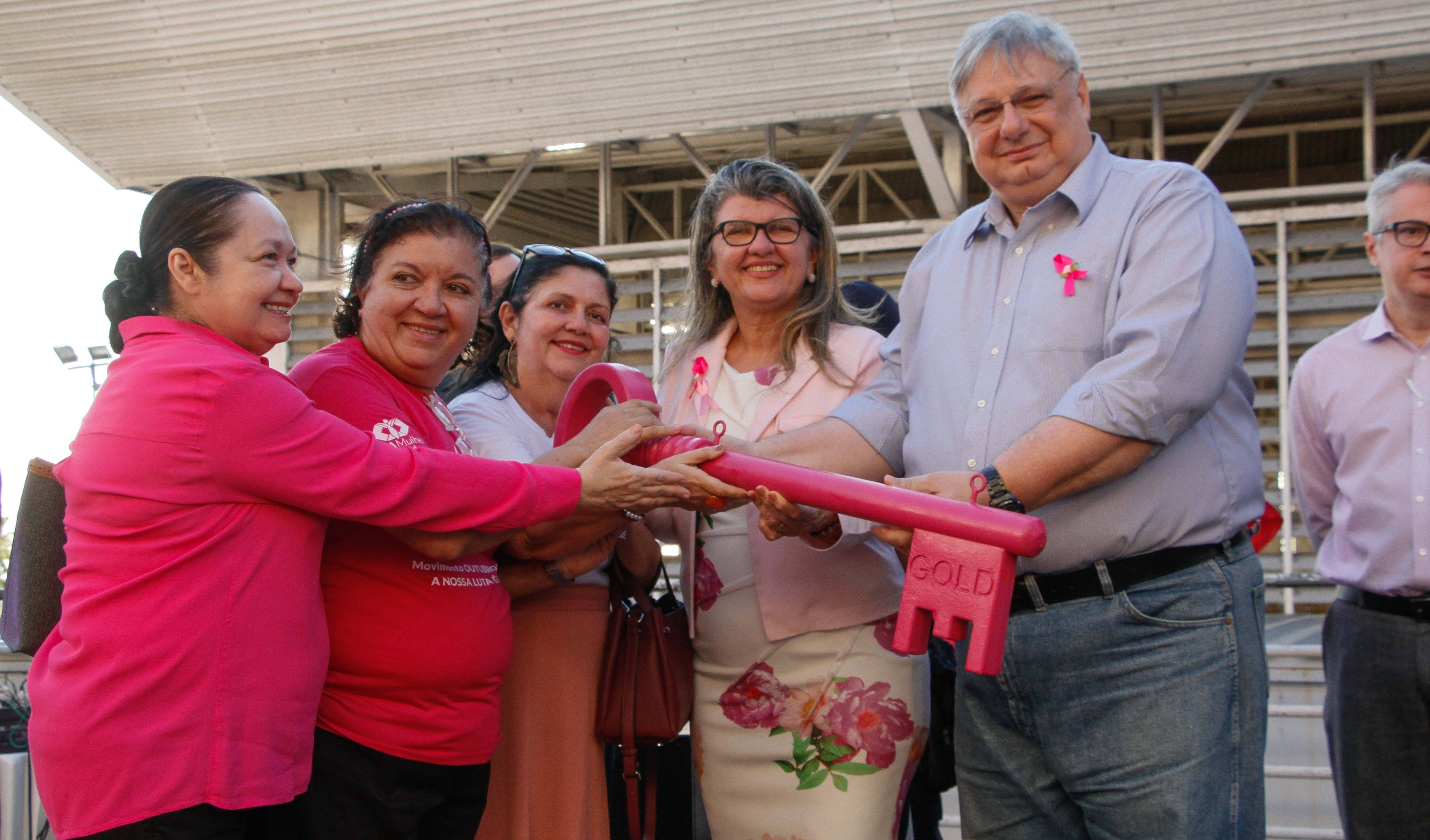 Moroni e mulheres em cima de palco segurando chave gigante cor de rosa