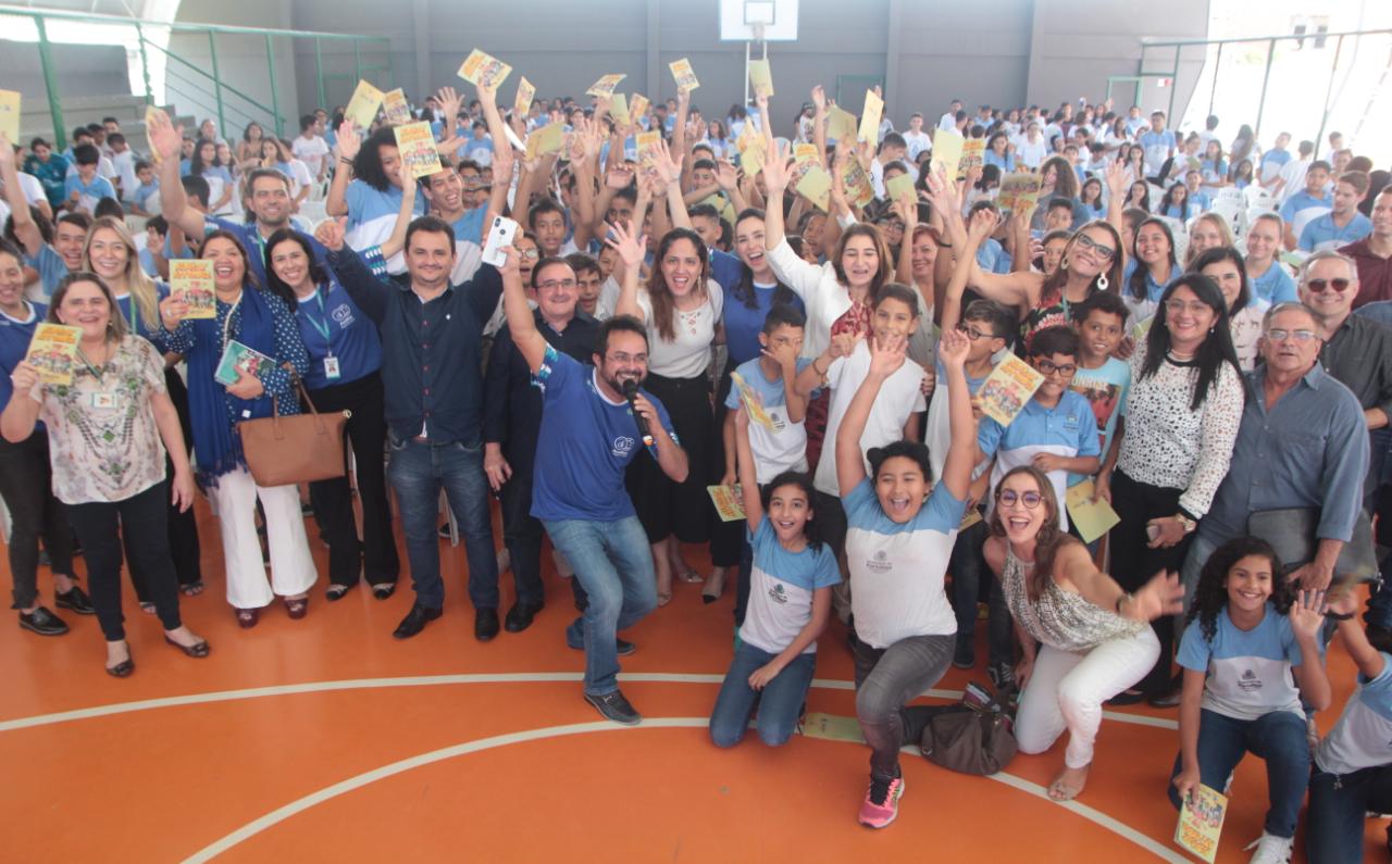 Grupo de alunos com as mãos pra cima na quadra da escola