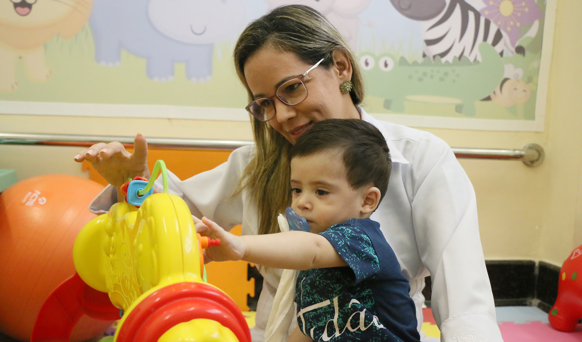 Mulher de jaleco brincando com menino