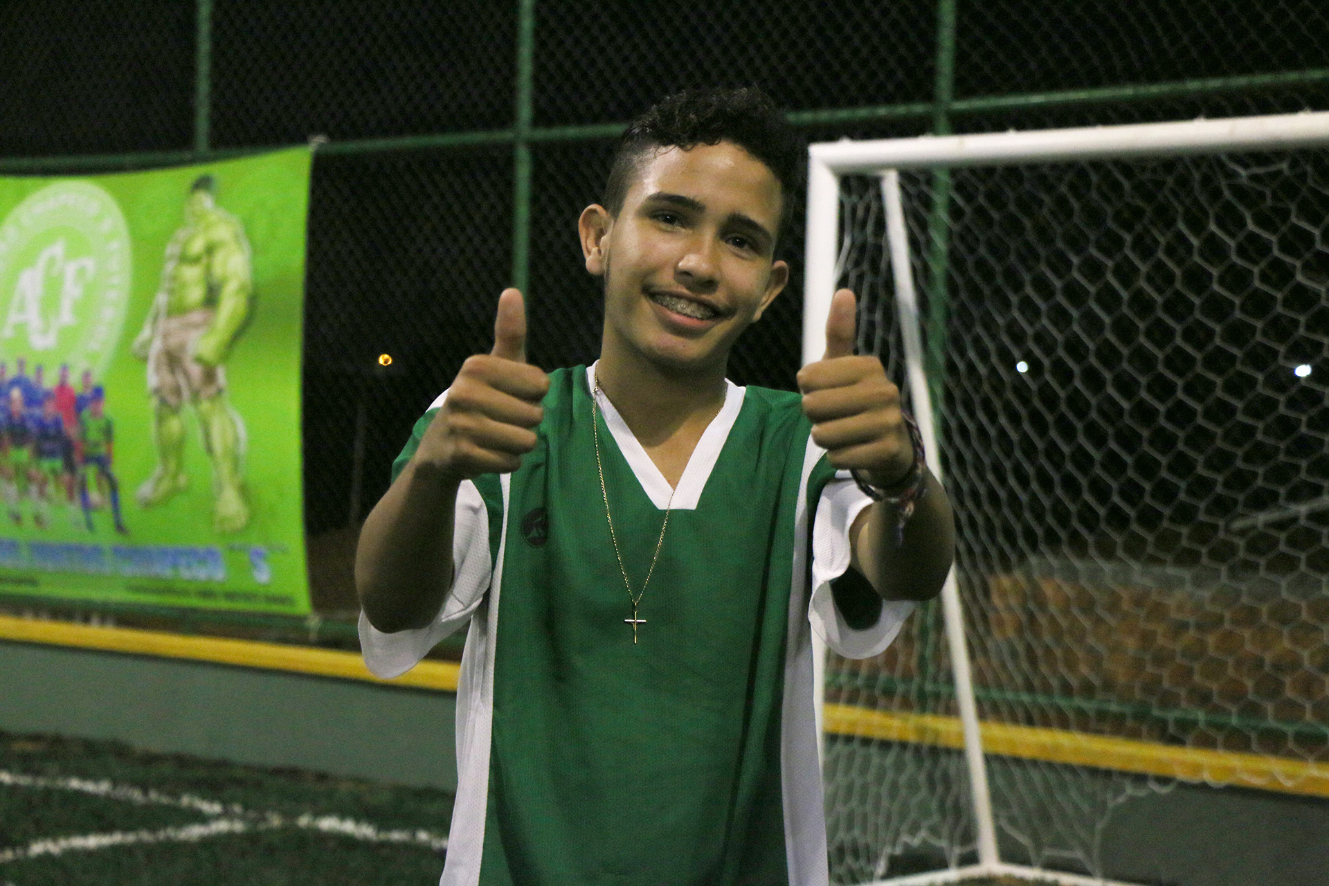 adolescente de camisa verde posa para a foto sorrindo