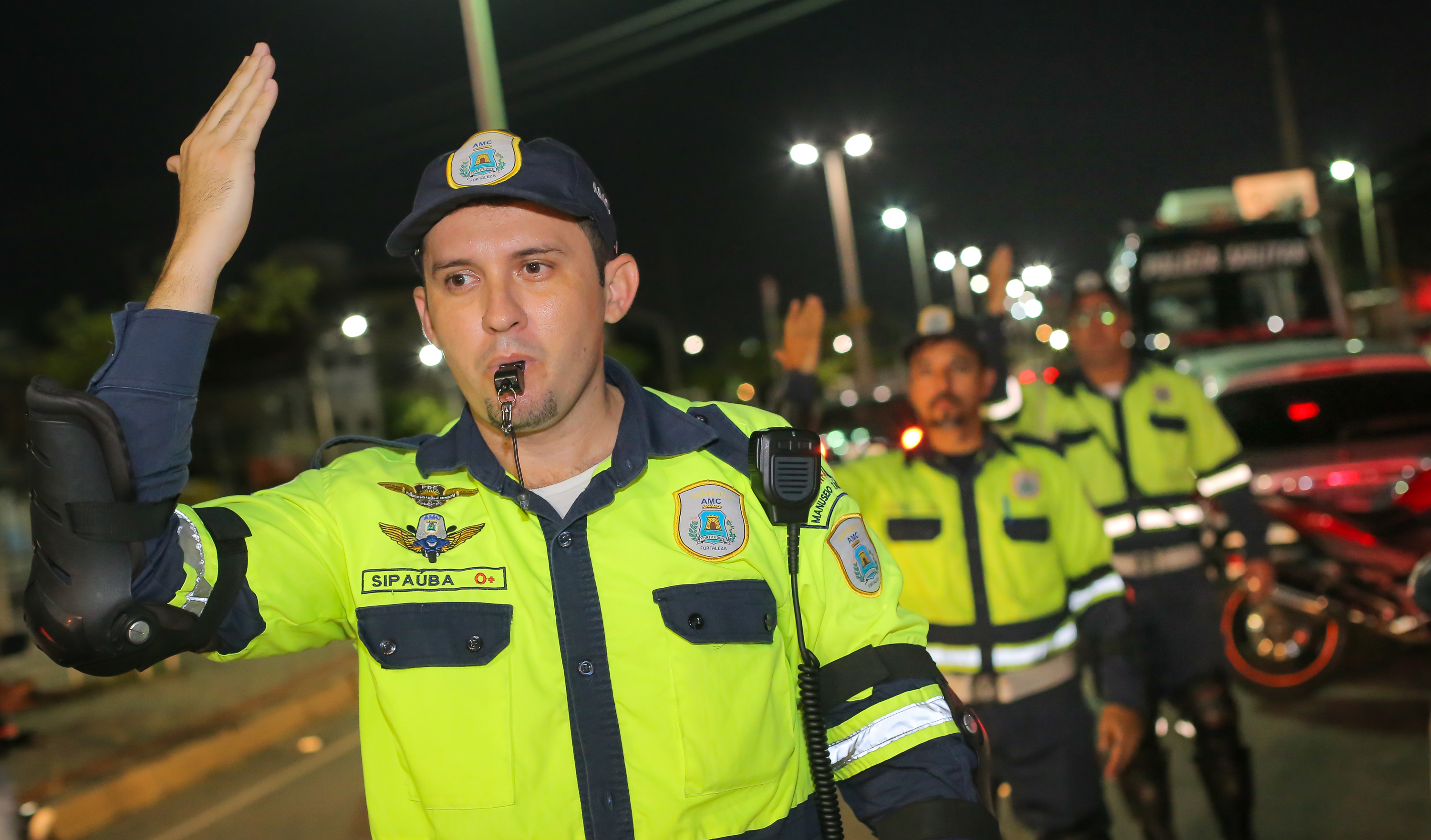 Três agentes de trânsito sinalizando para carros