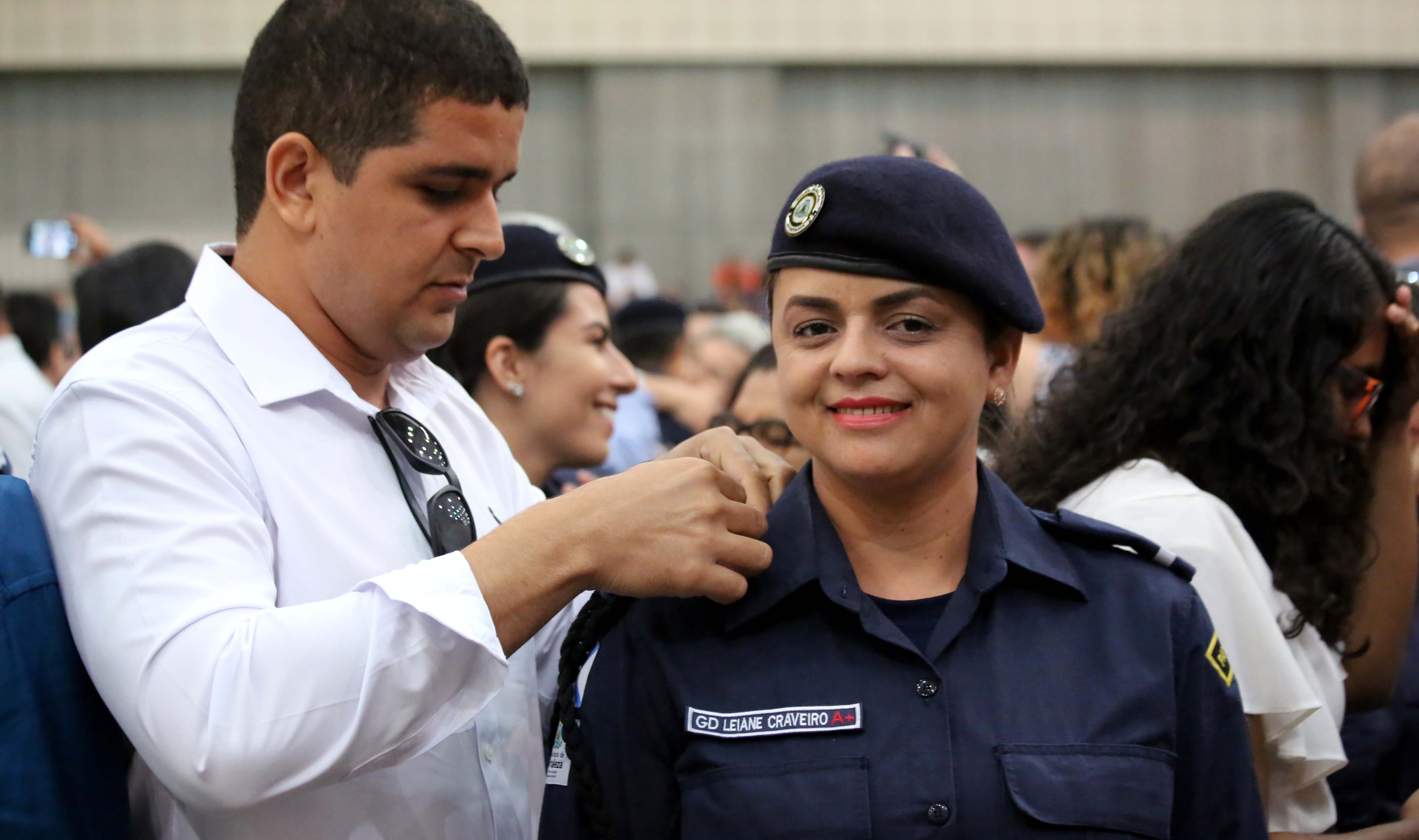 Guarda mulher sorrindo enquanto homem põe a mão em seu ombro