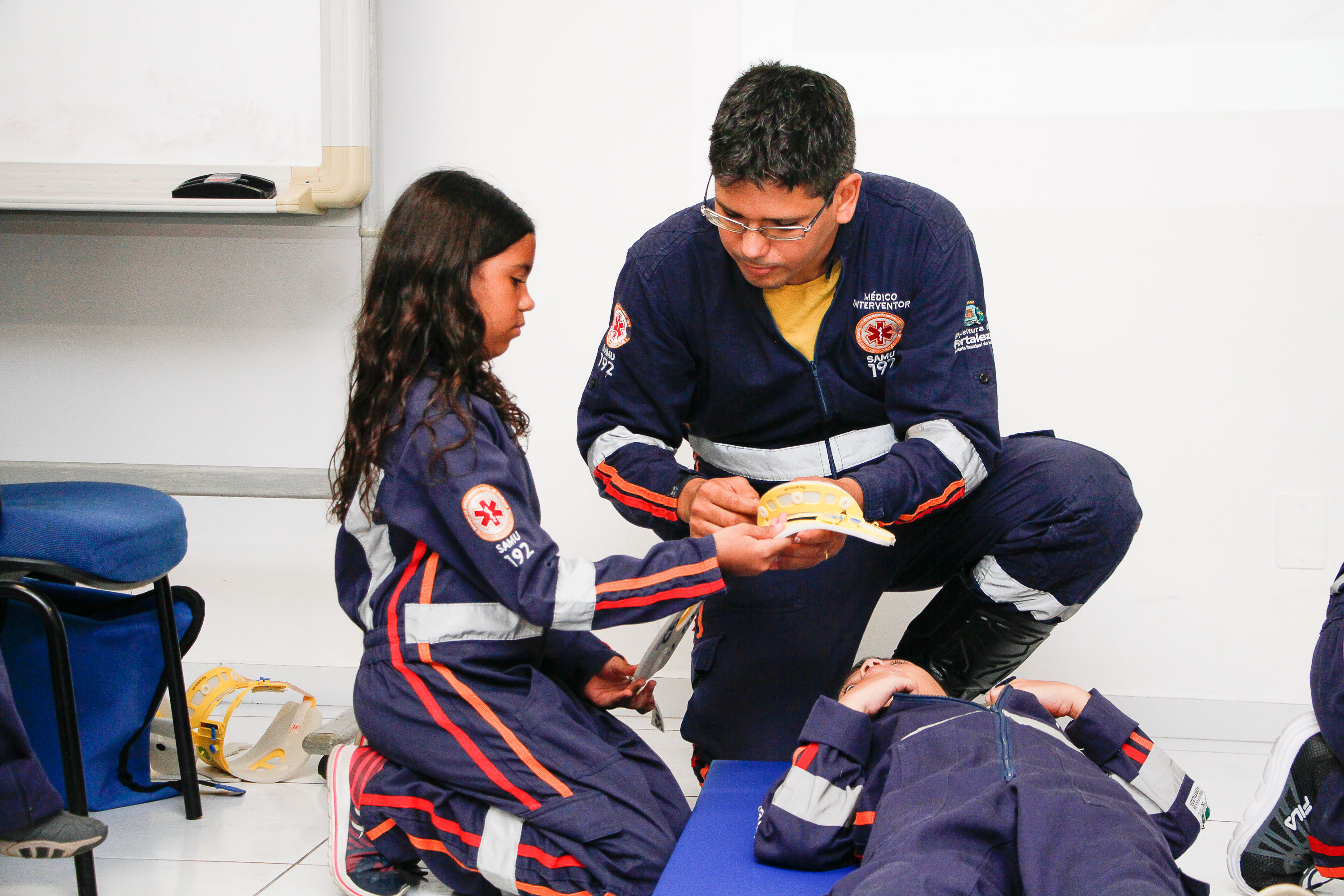 Instrutor orientando menina a usar colar cervical em garoto deitado