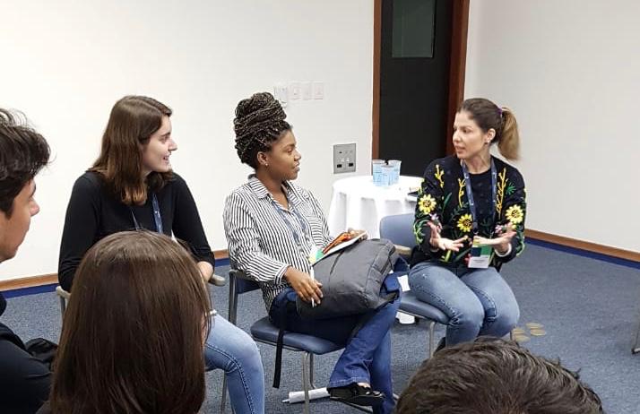 três pessoas sentadas em uma sala de aula