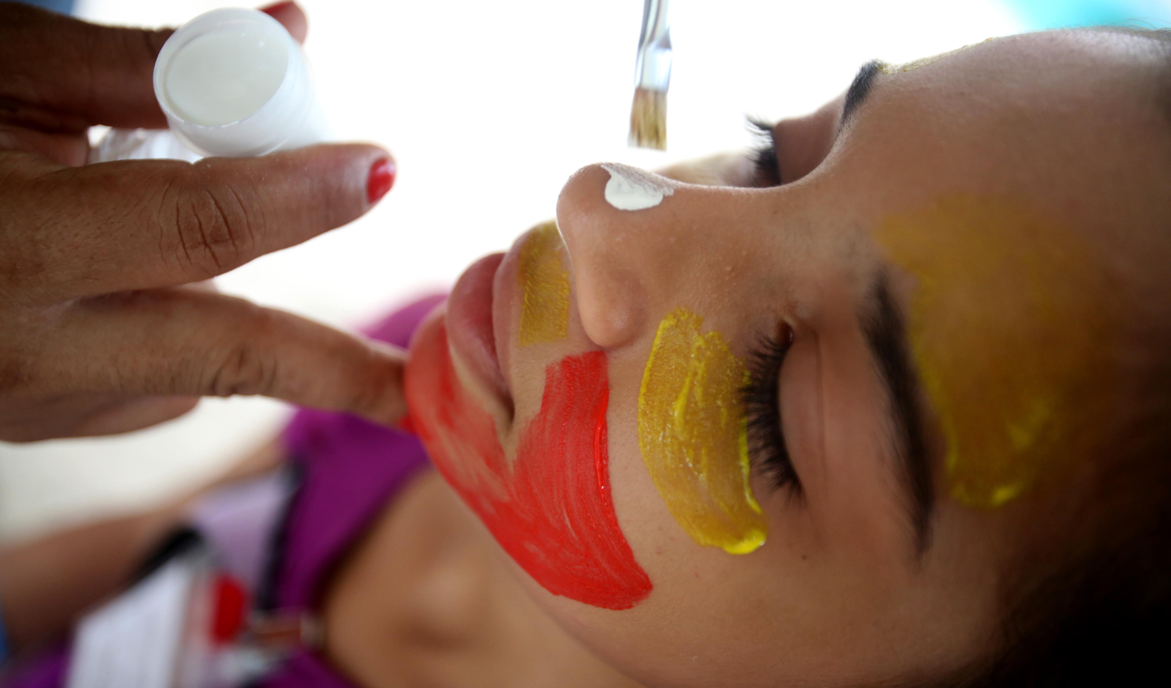 criança pintando o rosto de palhaço