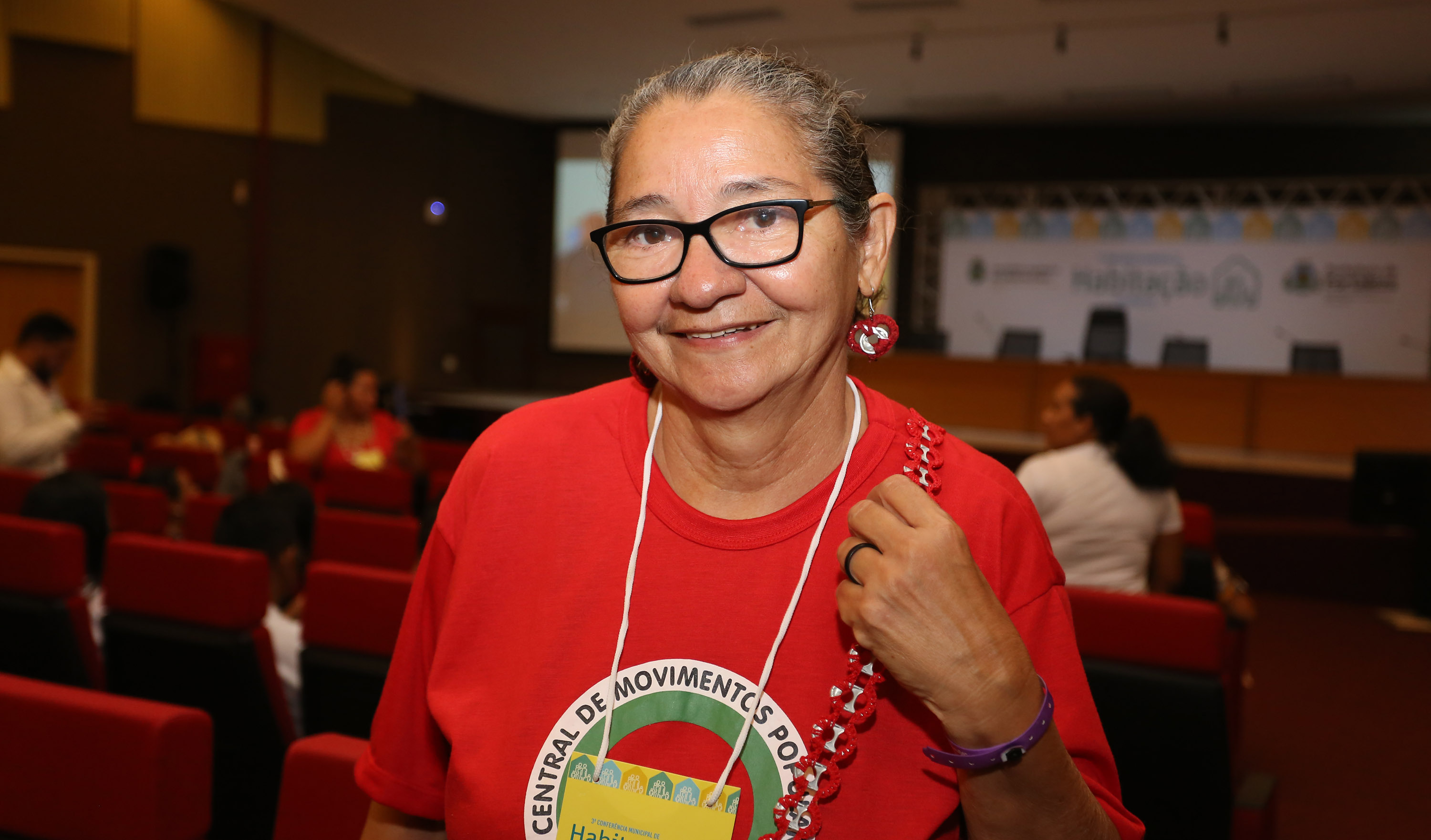 Senhora de óculos sorrindo para a foto