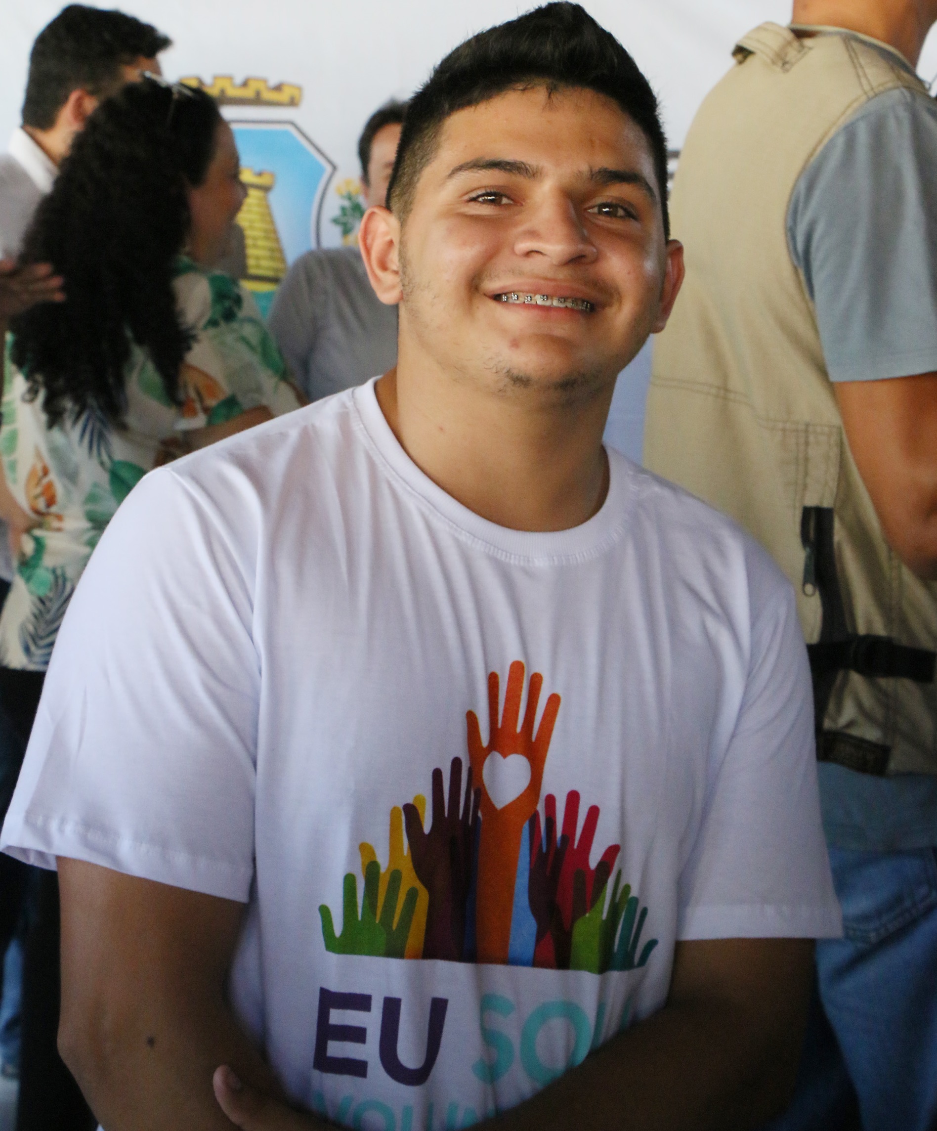 Rapaz sorrindo para a foto vestinho a blusa de voluntário