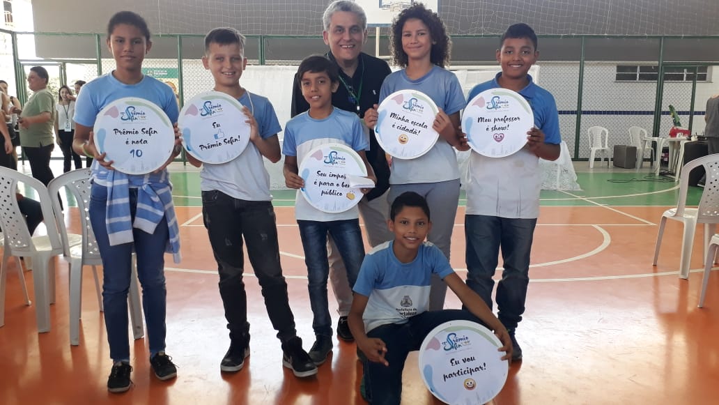 Secretário em pé ao lado de alunos em quadra de esportes