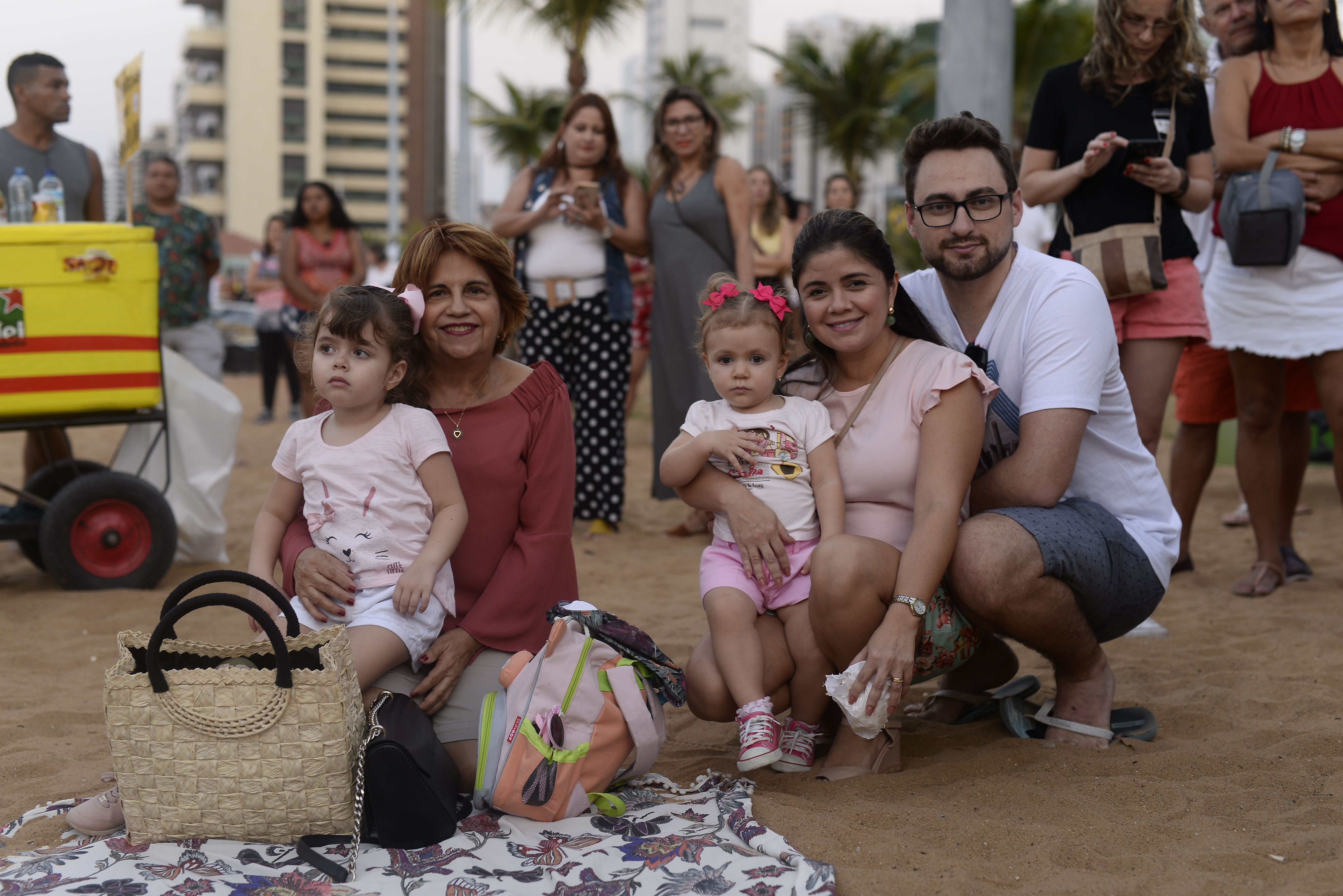 Família sentada na areia (senhora, mulher, homem e duas meninas)