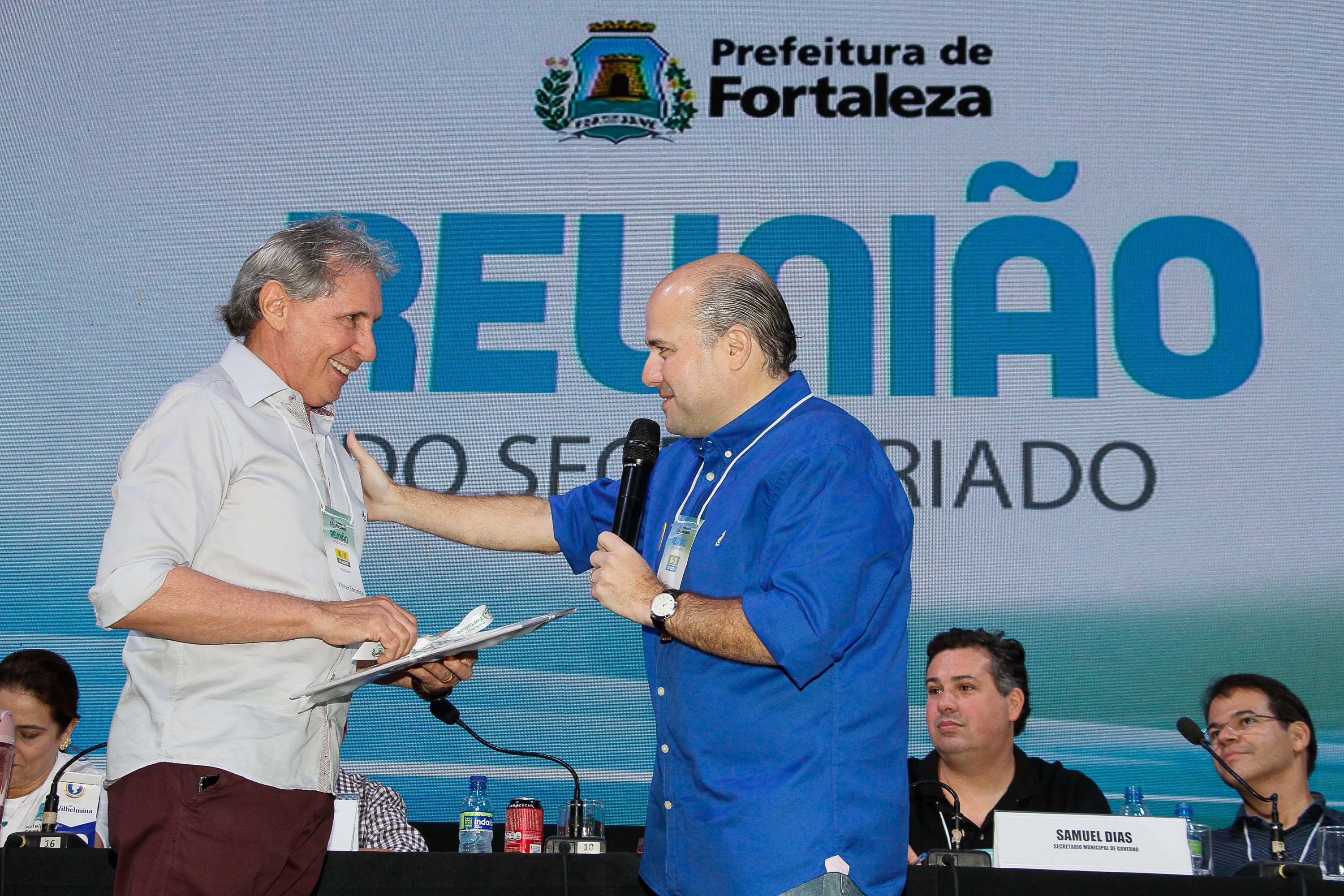 Prefeito apertando a mão de senhor em cima do palco