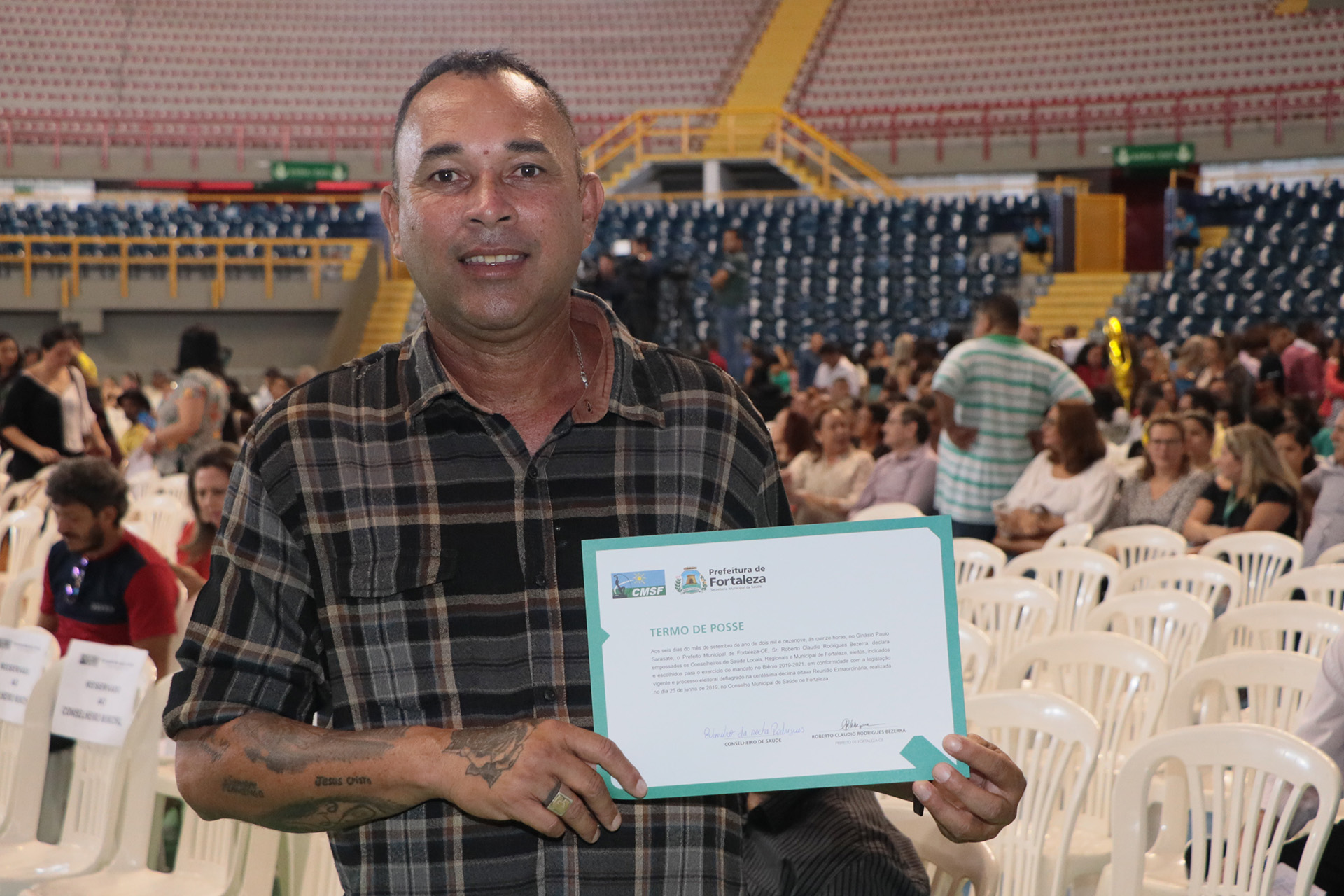 Homem posando para foto segurando termo de posse