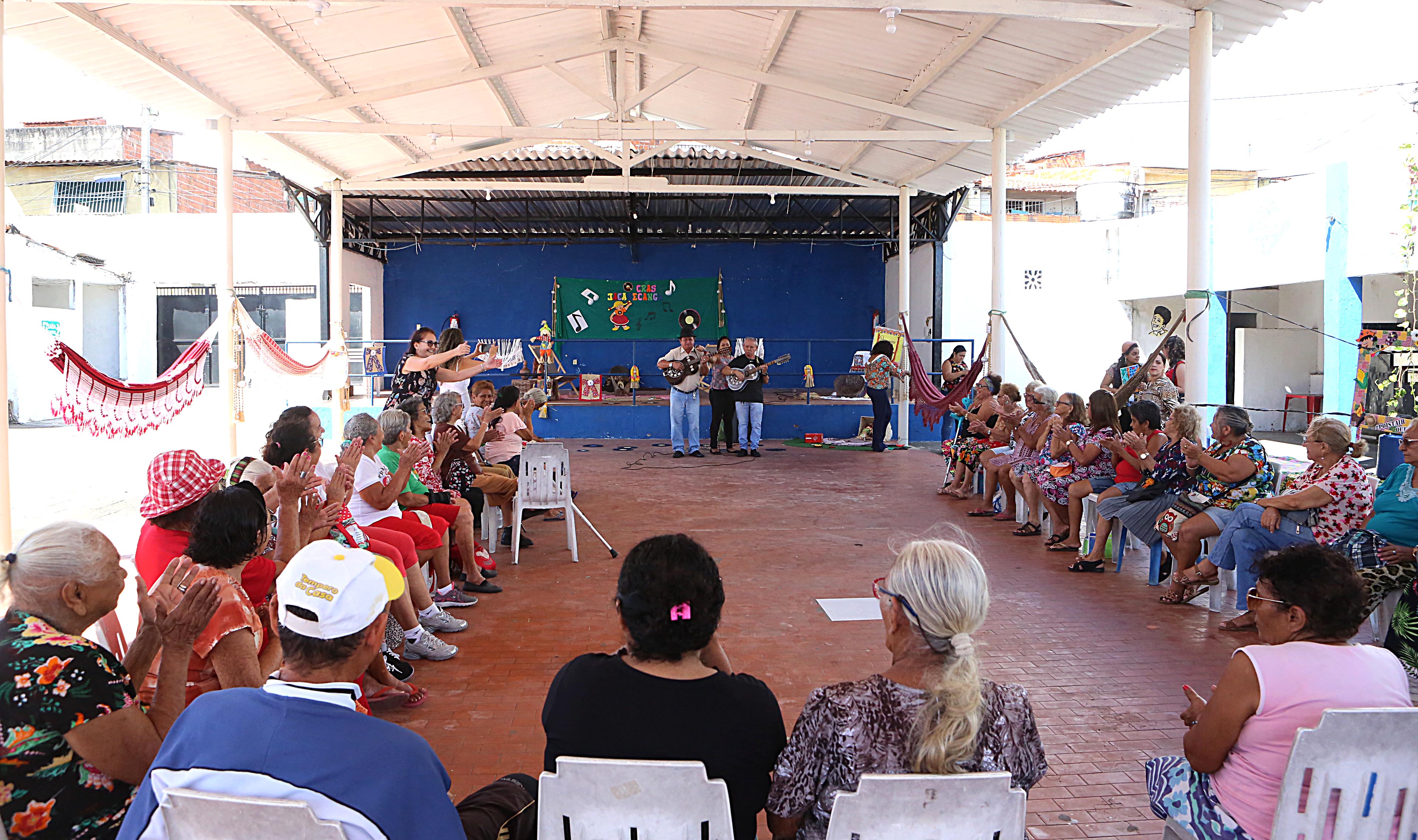 uma roda de idoso assiste a apresentação de um violeiro