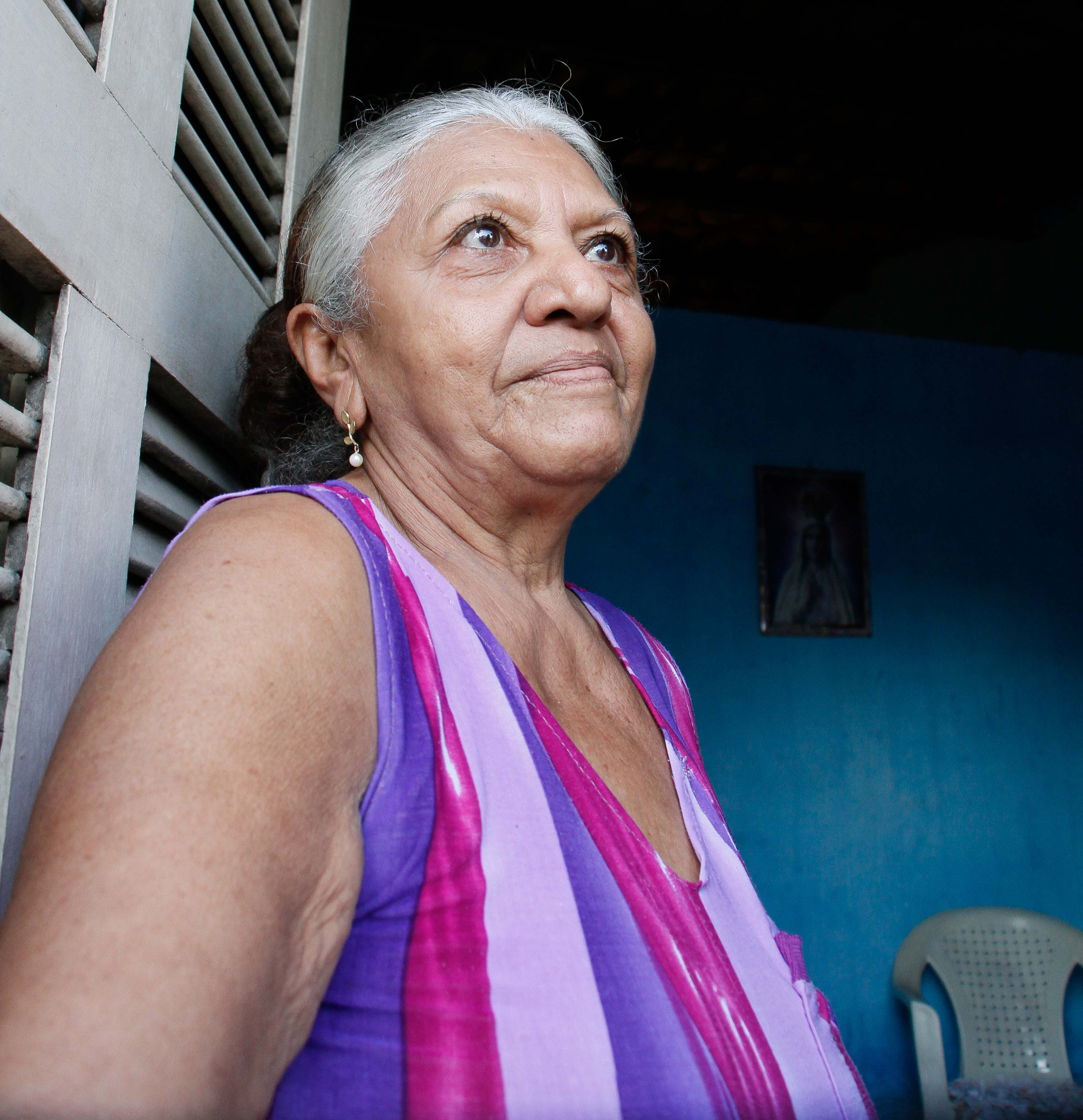 senhora encostada em janela olhando pra rua