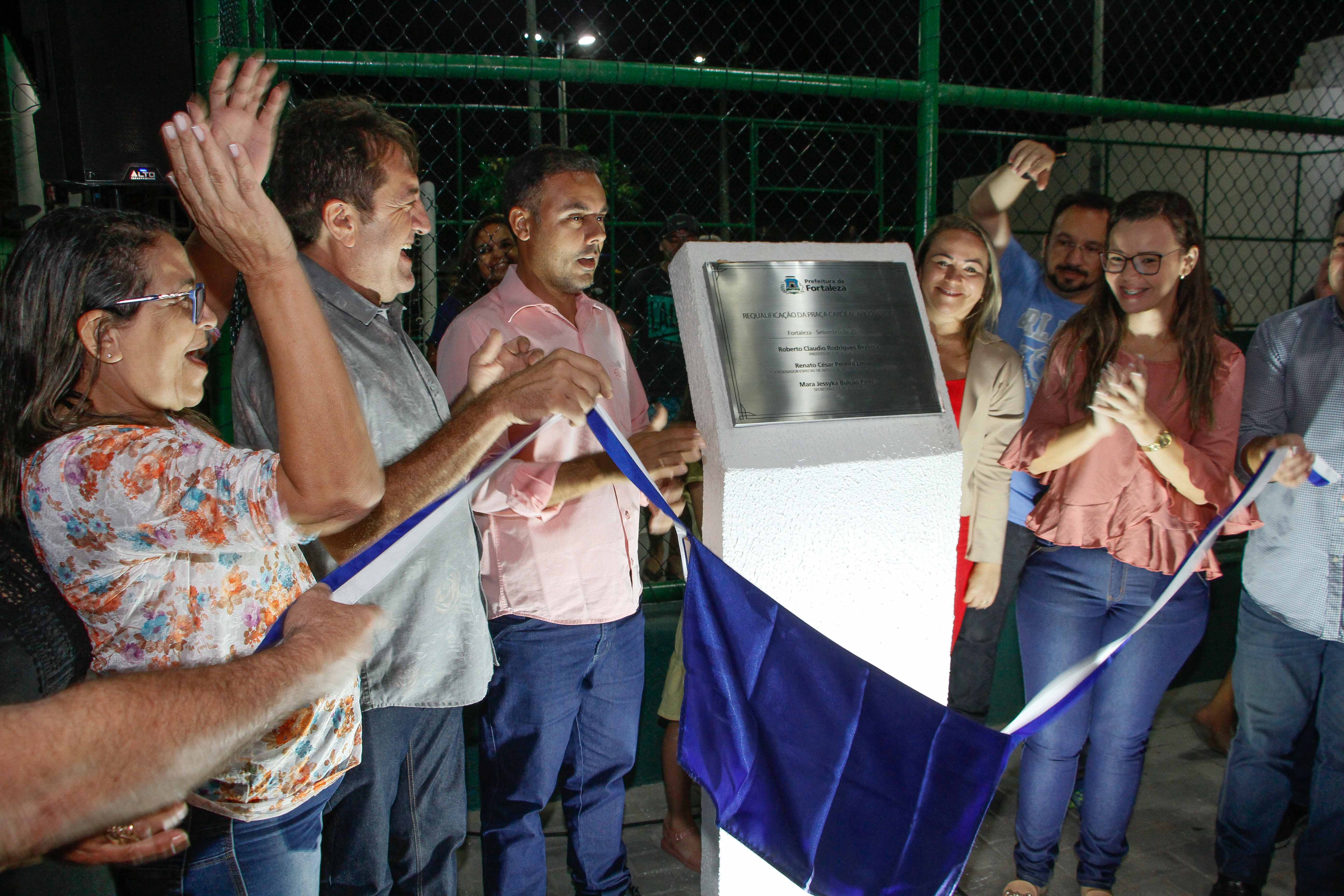 pessoas descerrando a placa e aplaudindo