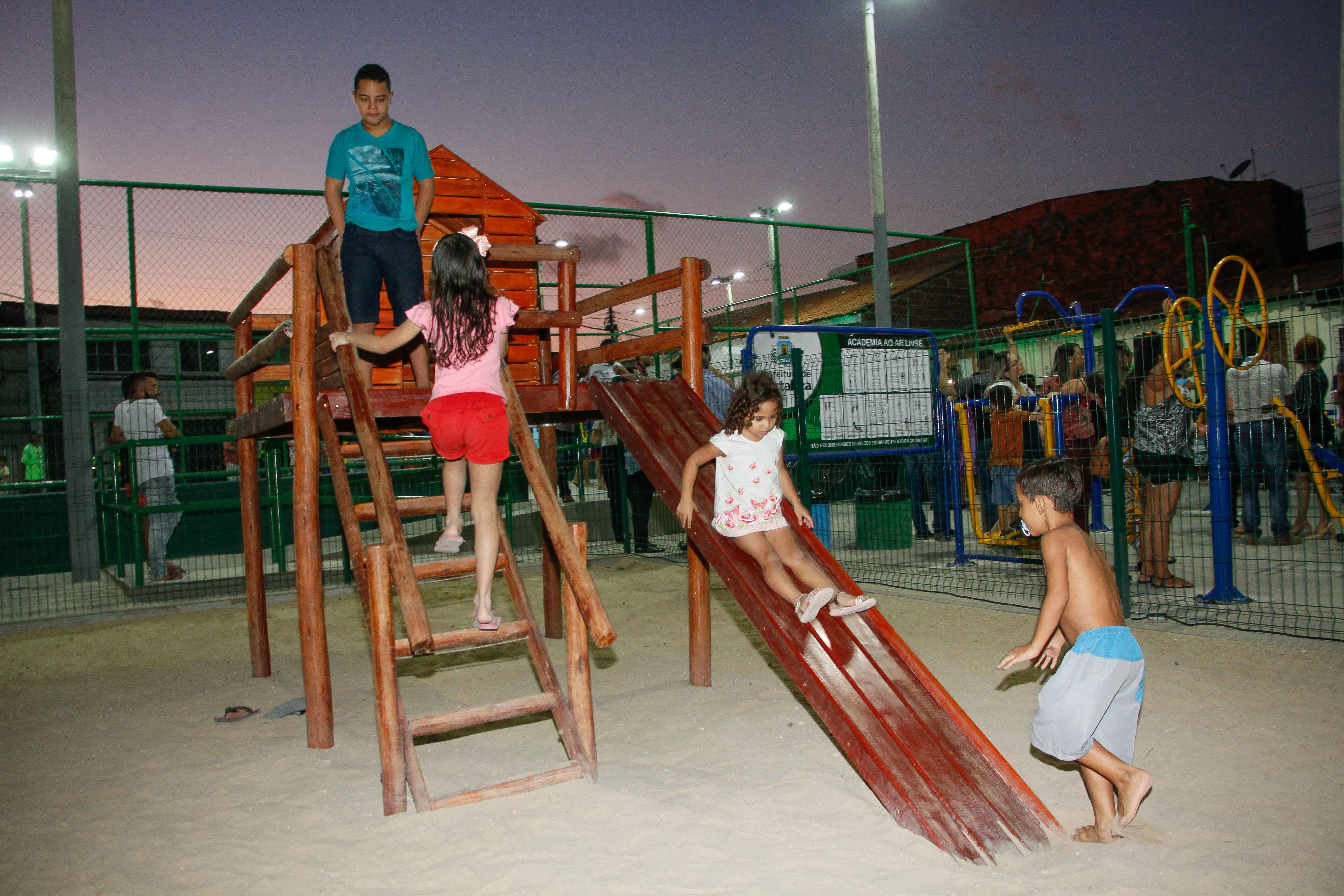 quatro crianças brincando em parquinho na praça