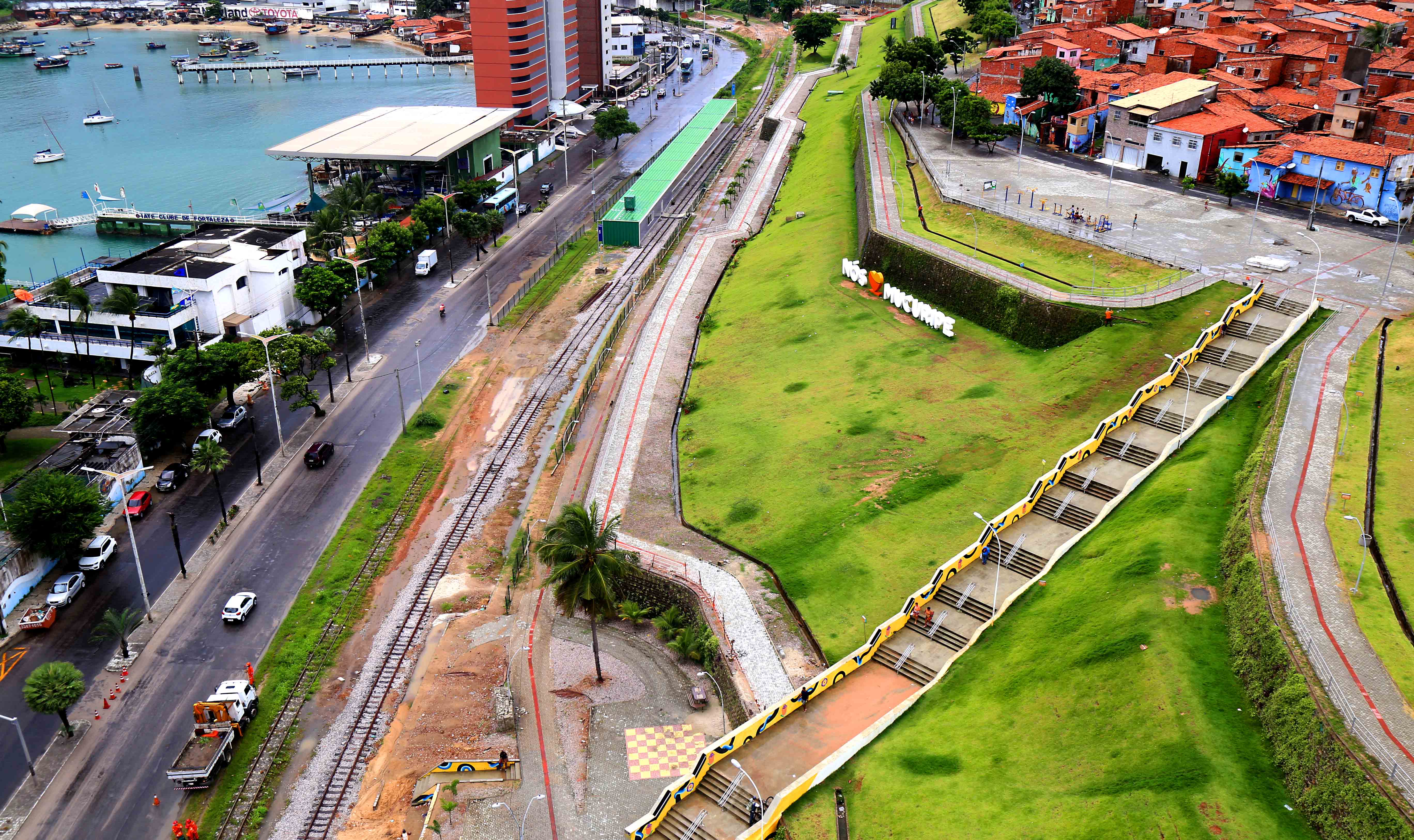 Trecho de avenida à beira mar e morro gramado ao lado