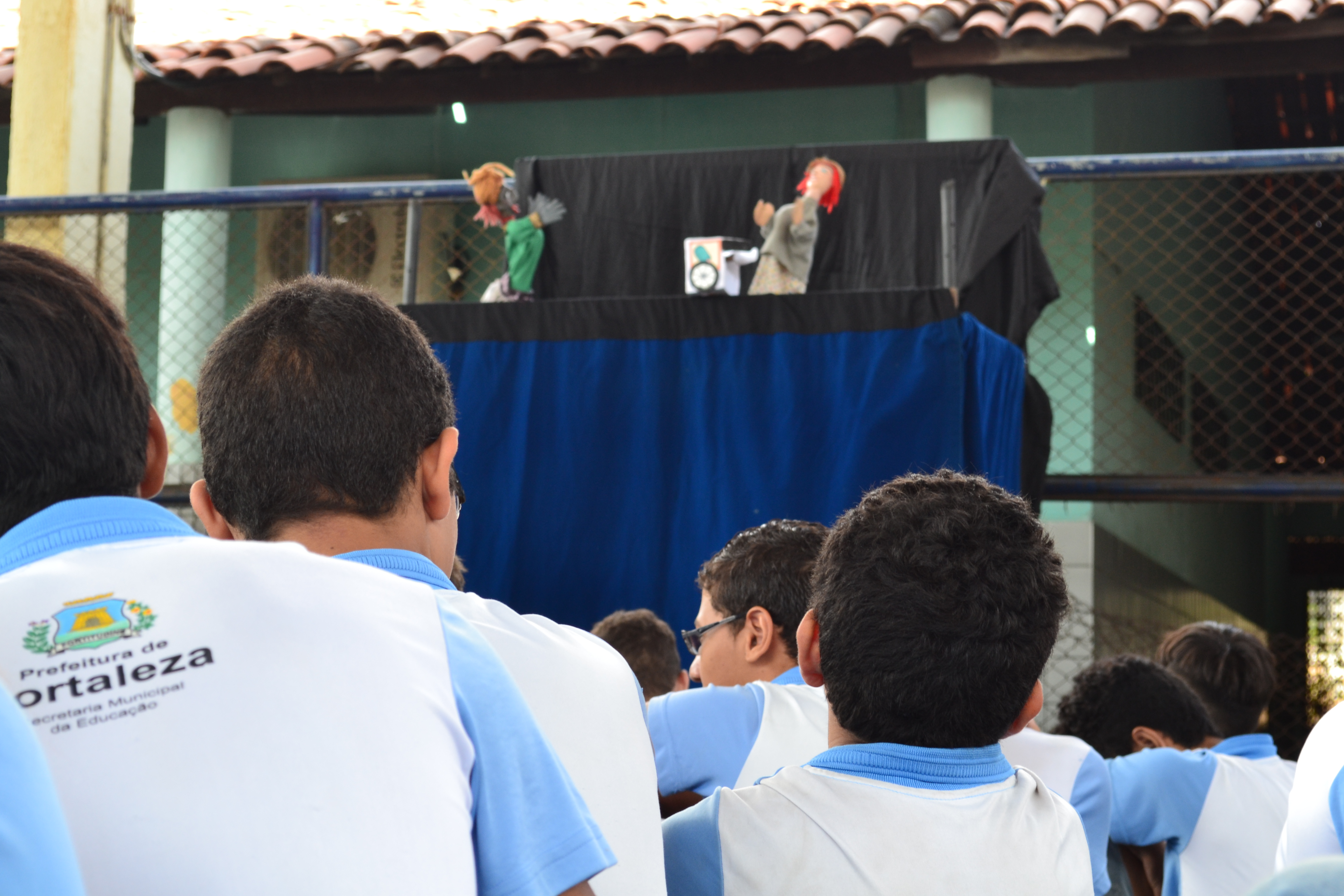 Crianças de costas assistindo a teatro de fantoches