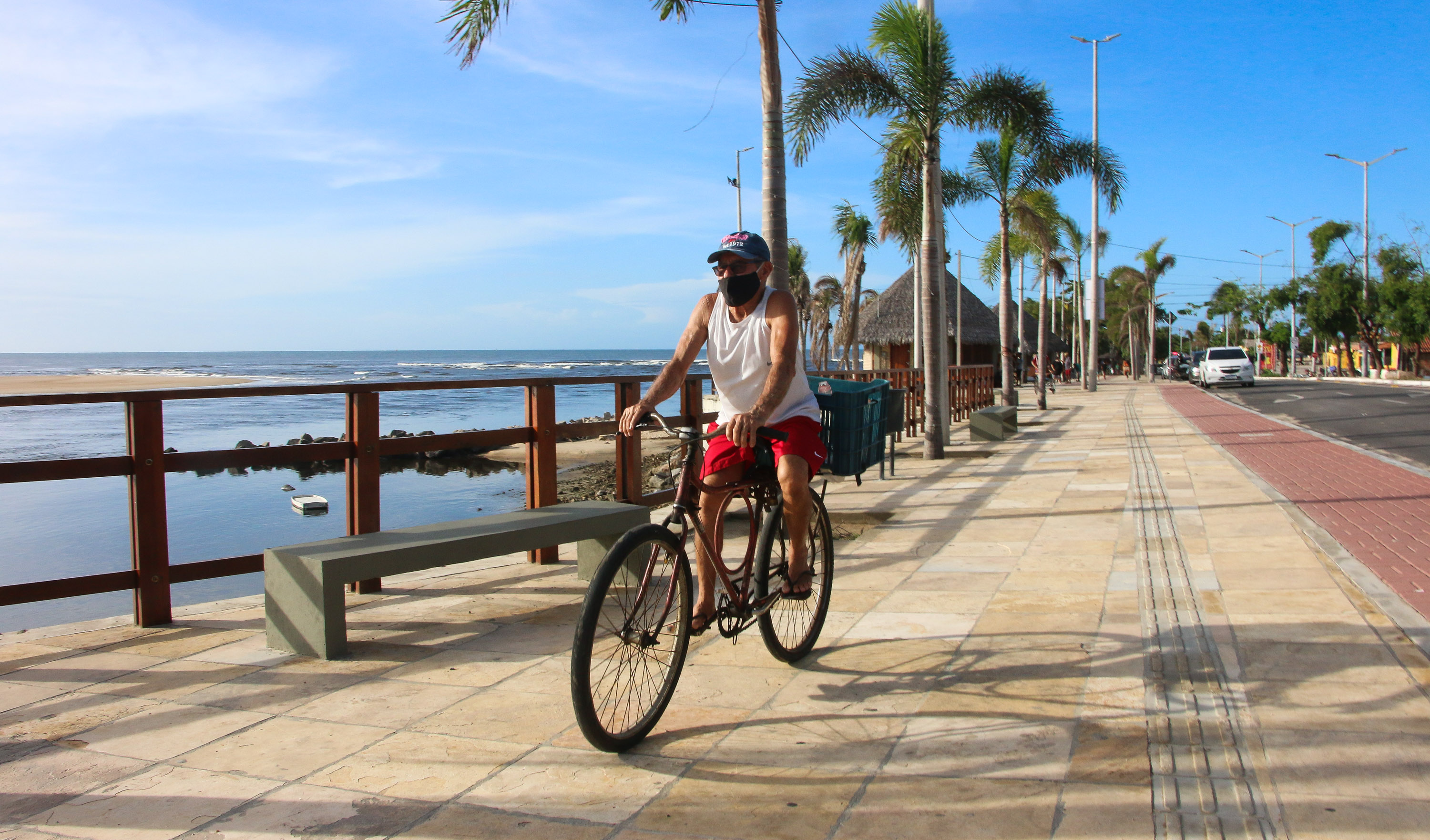 homem andando de bicicleta em um calçadão na praia