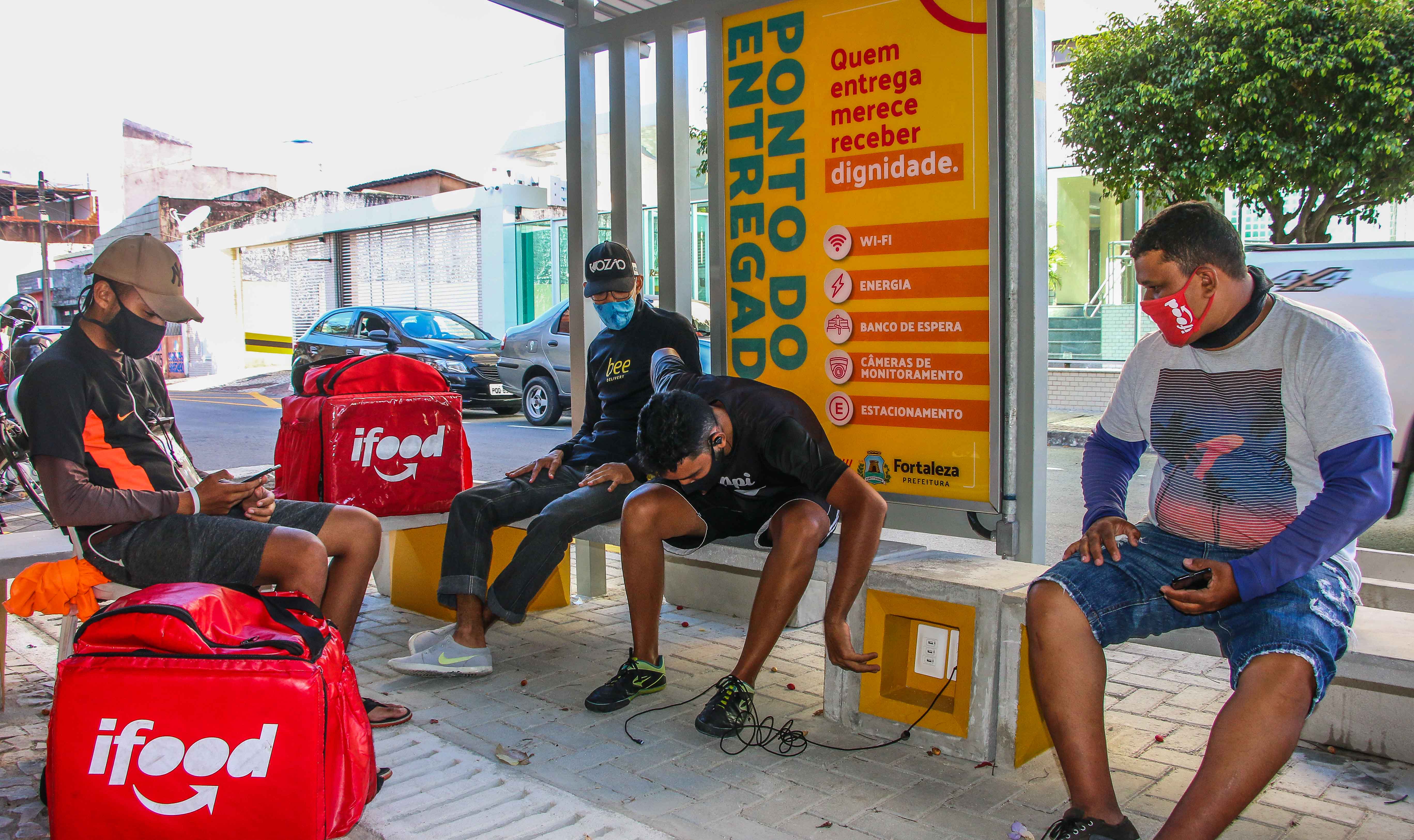 entregadores sentados no banco do ponto do entregador