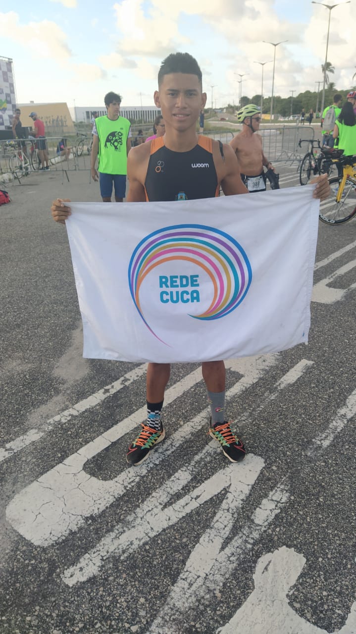 foto vestido com roupa esportiva segura um bandeira da rede cuca