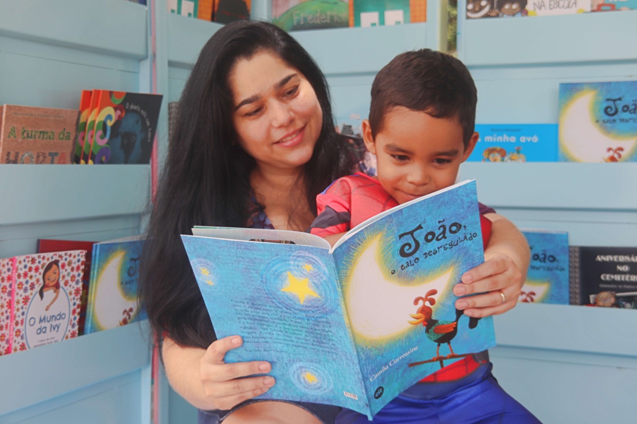 mulher com garoto sentado no colo lendo livro