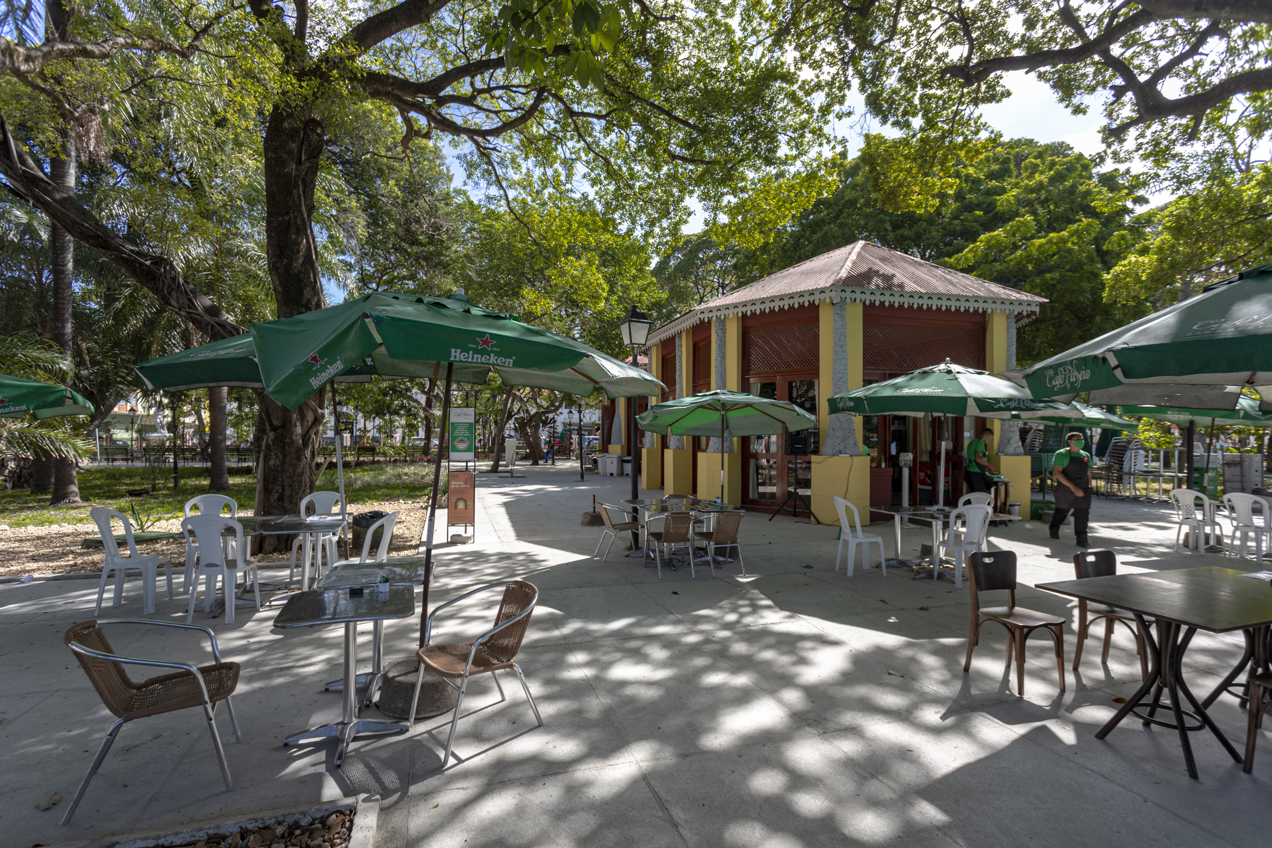 quiosque de restaurante com mesas com guarda-sóis em frente e muitas árvores