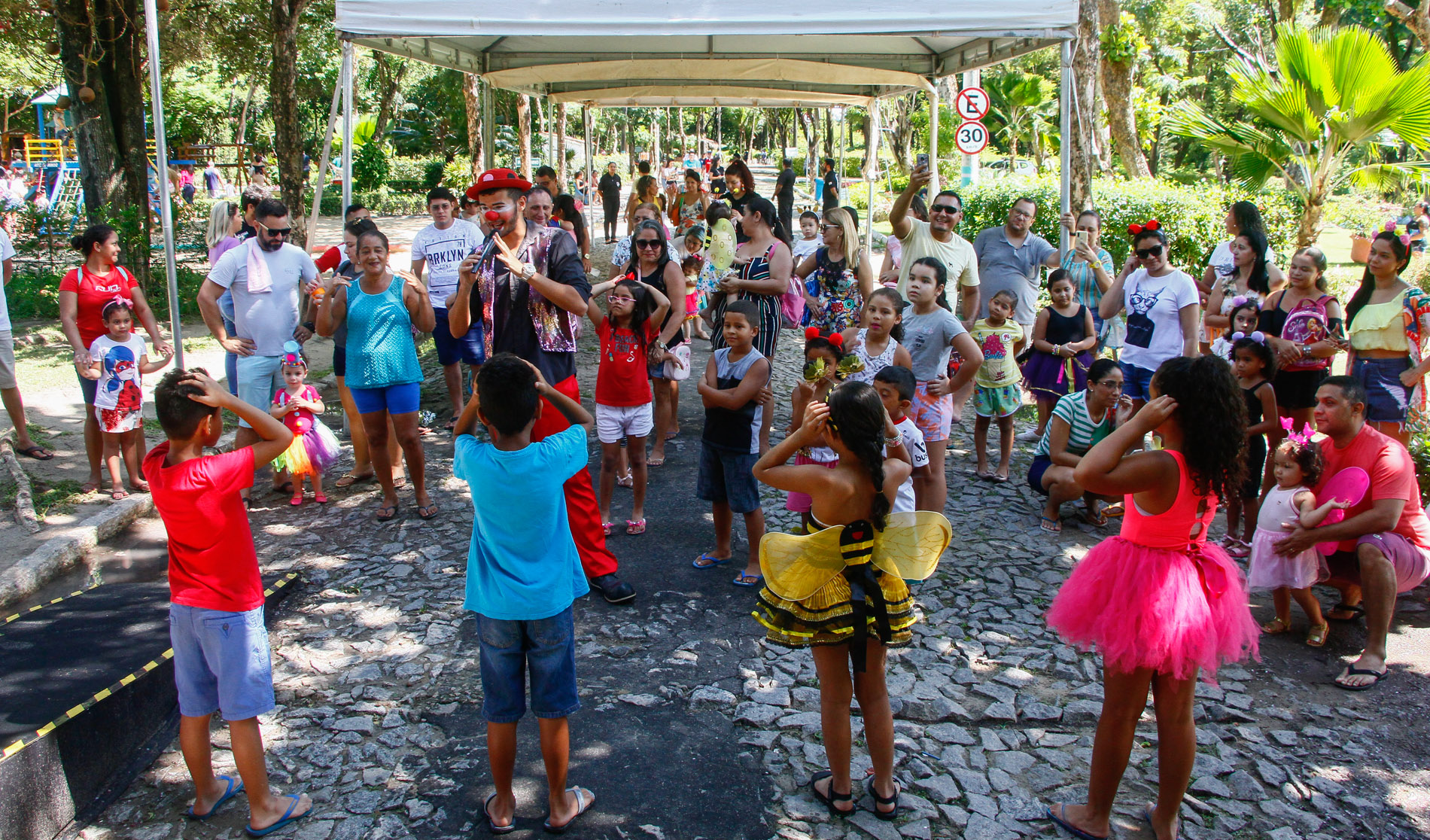 palhaço no meio de roda formada por crianças fantasiadas