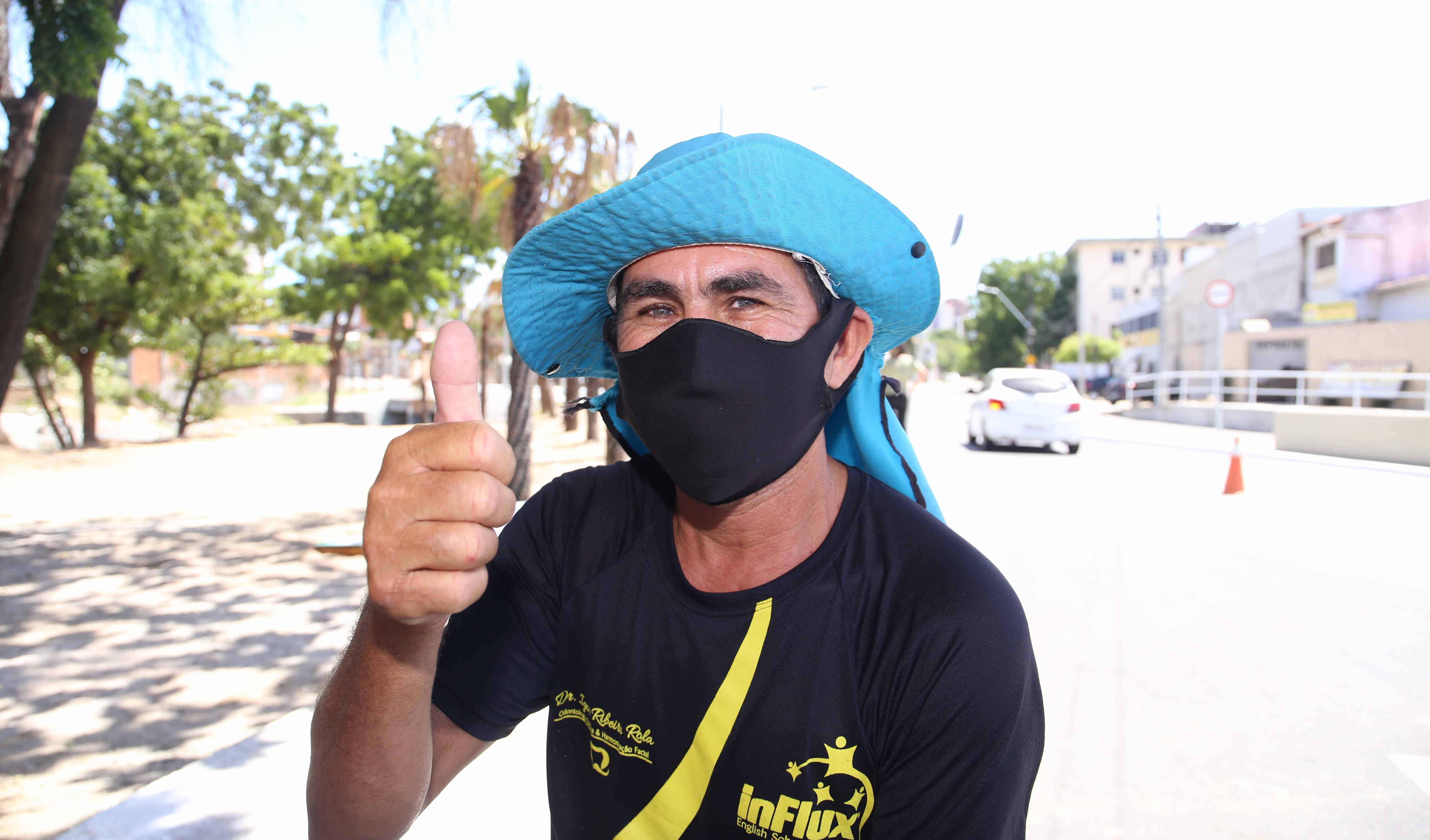 homem de chapéu e máscara posando para a foto fazendo sinal de legal com a mão