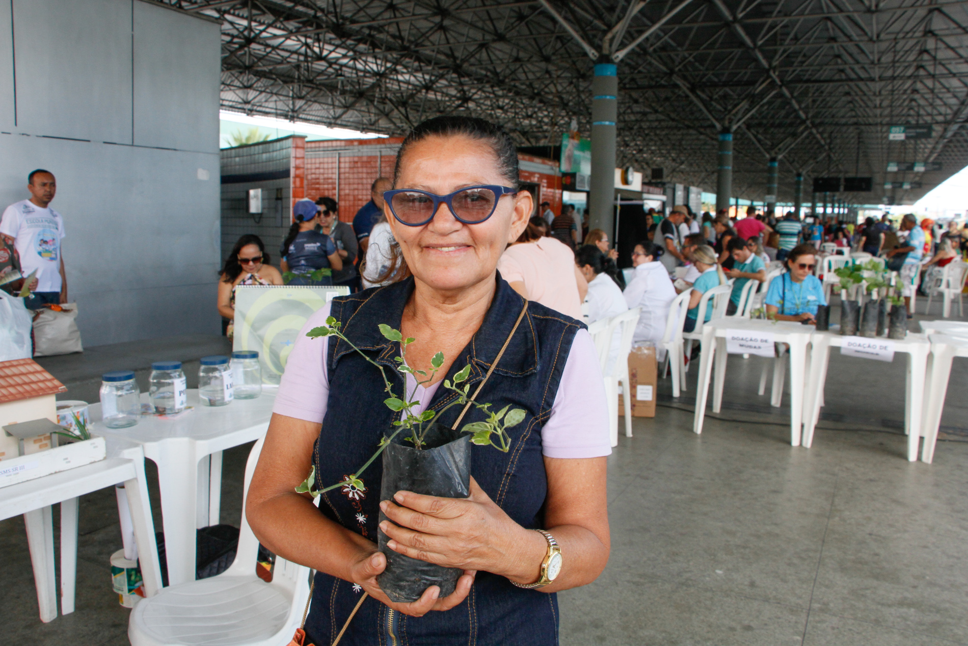 senhora segurando muda de plantas e sorrindo