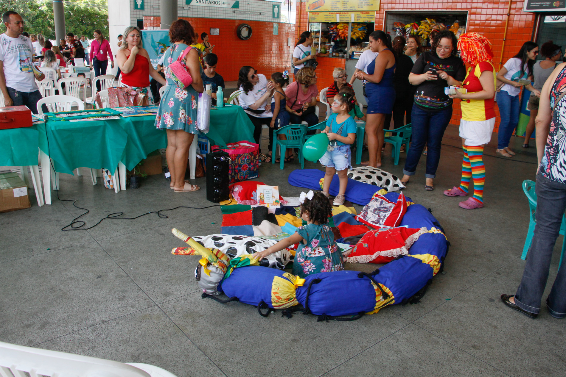 crianças brincando com brinquedos no chão e pessoas em pé ao redor