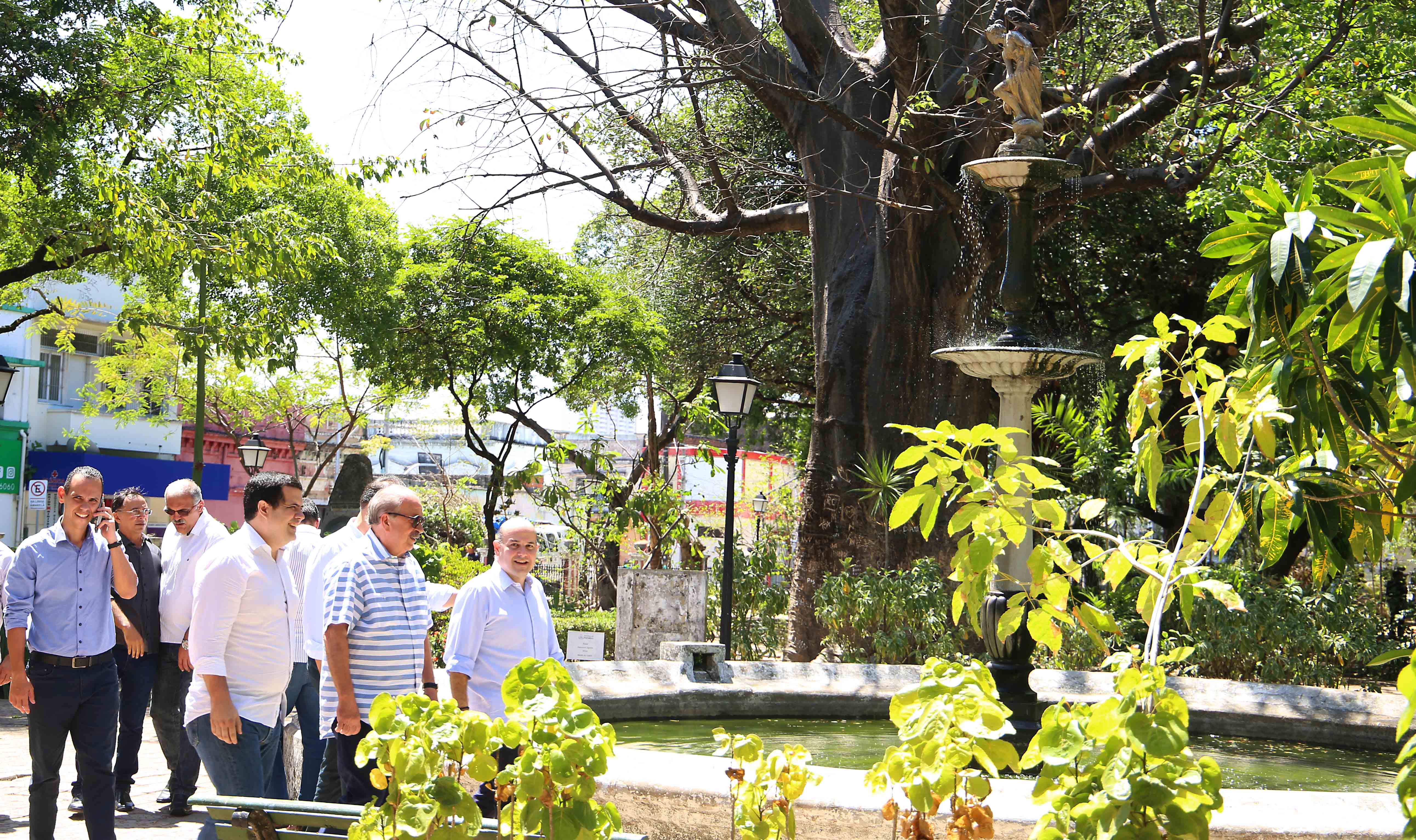 prefeito andando pela praça ao lado de pessoas