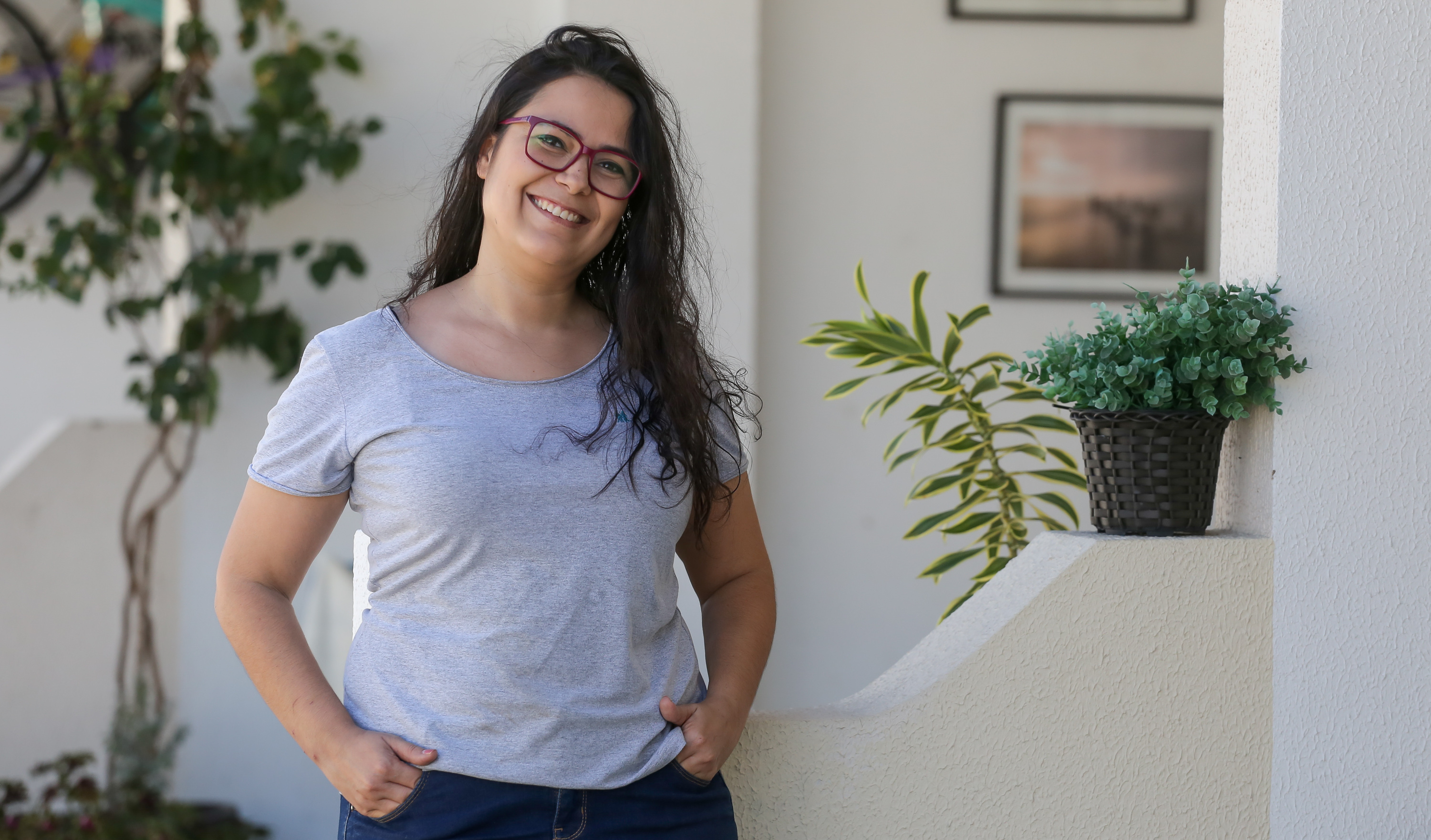 mulher em pé com as mãos na cintura sorrindo para a foto