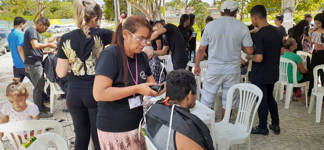 mulher cortando cabelo de homem em praça