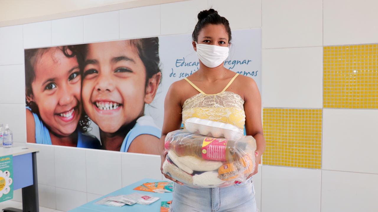 Uma mãe de aluno segurando um kit de alimentação