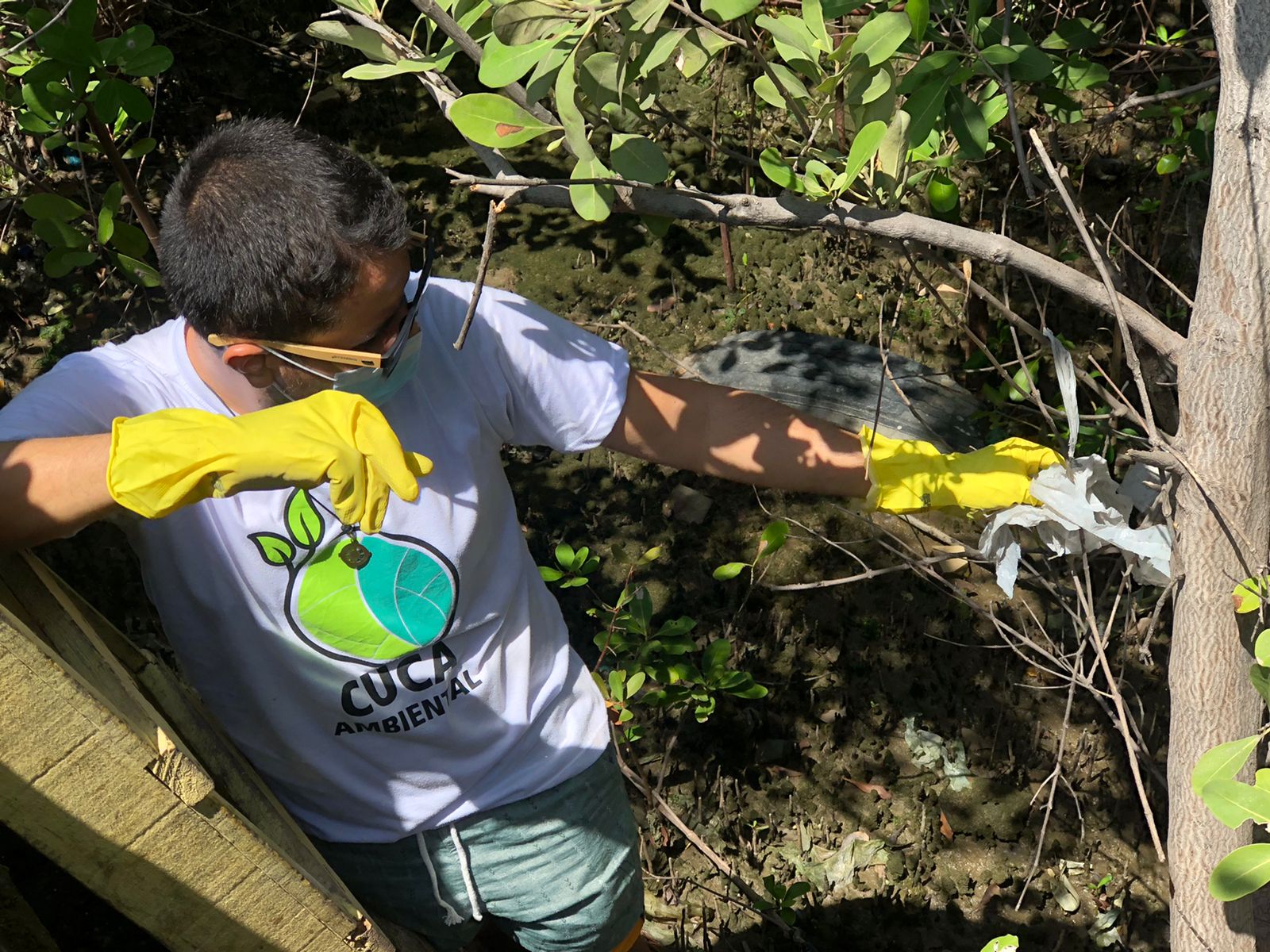 jovem coletando resíduos no mangue 