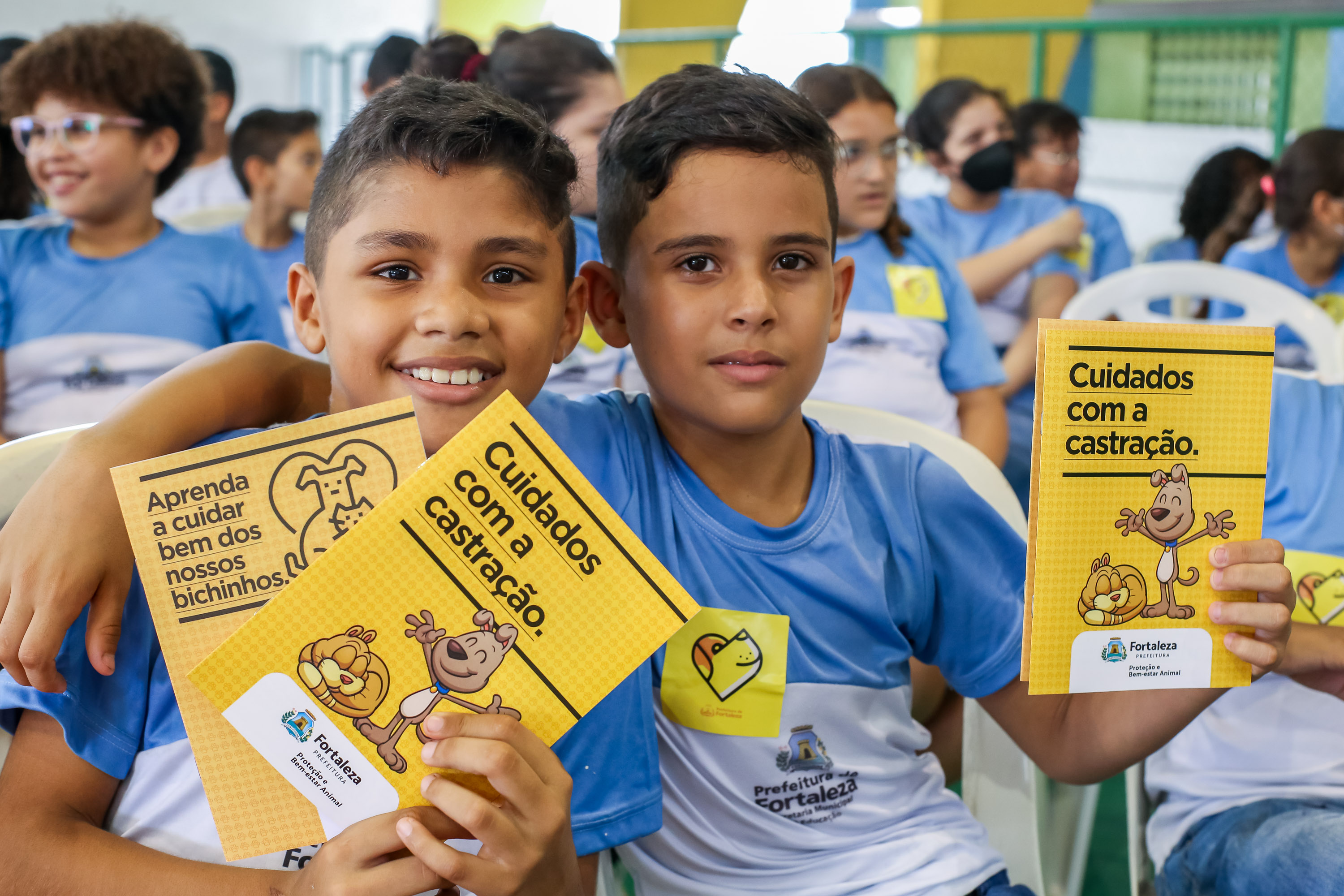 Dois meninos exibem cartilha sobre cuidados com os animais.