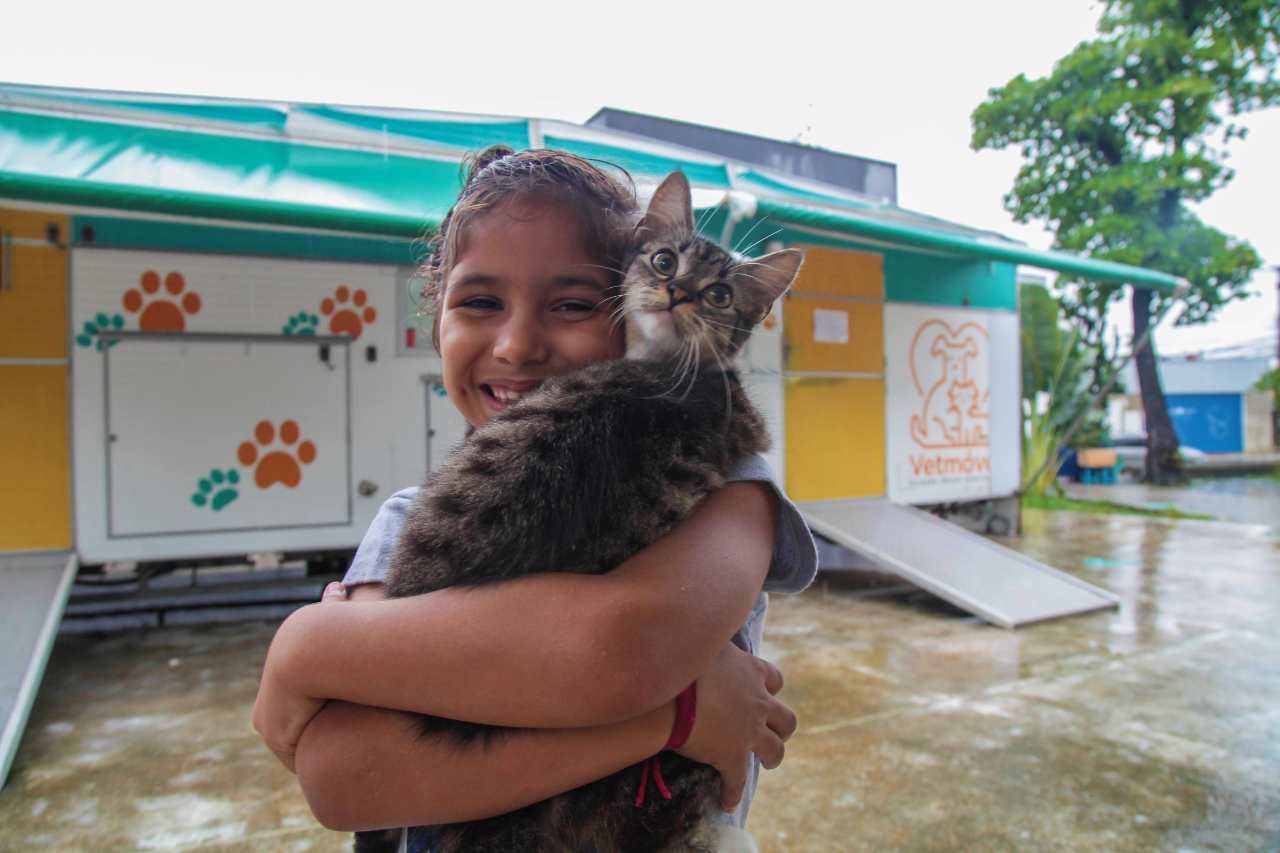 Menina segura gato na frente do VetMóvel