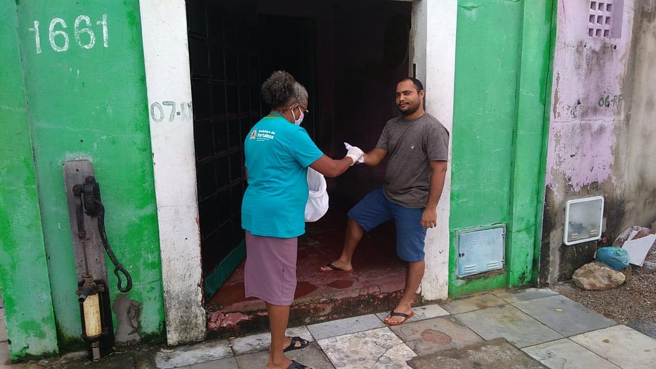 A Agente de Cidadania, Fátima Gomes, faz a distribuição de máscaras no bairro Cristo Redentor.