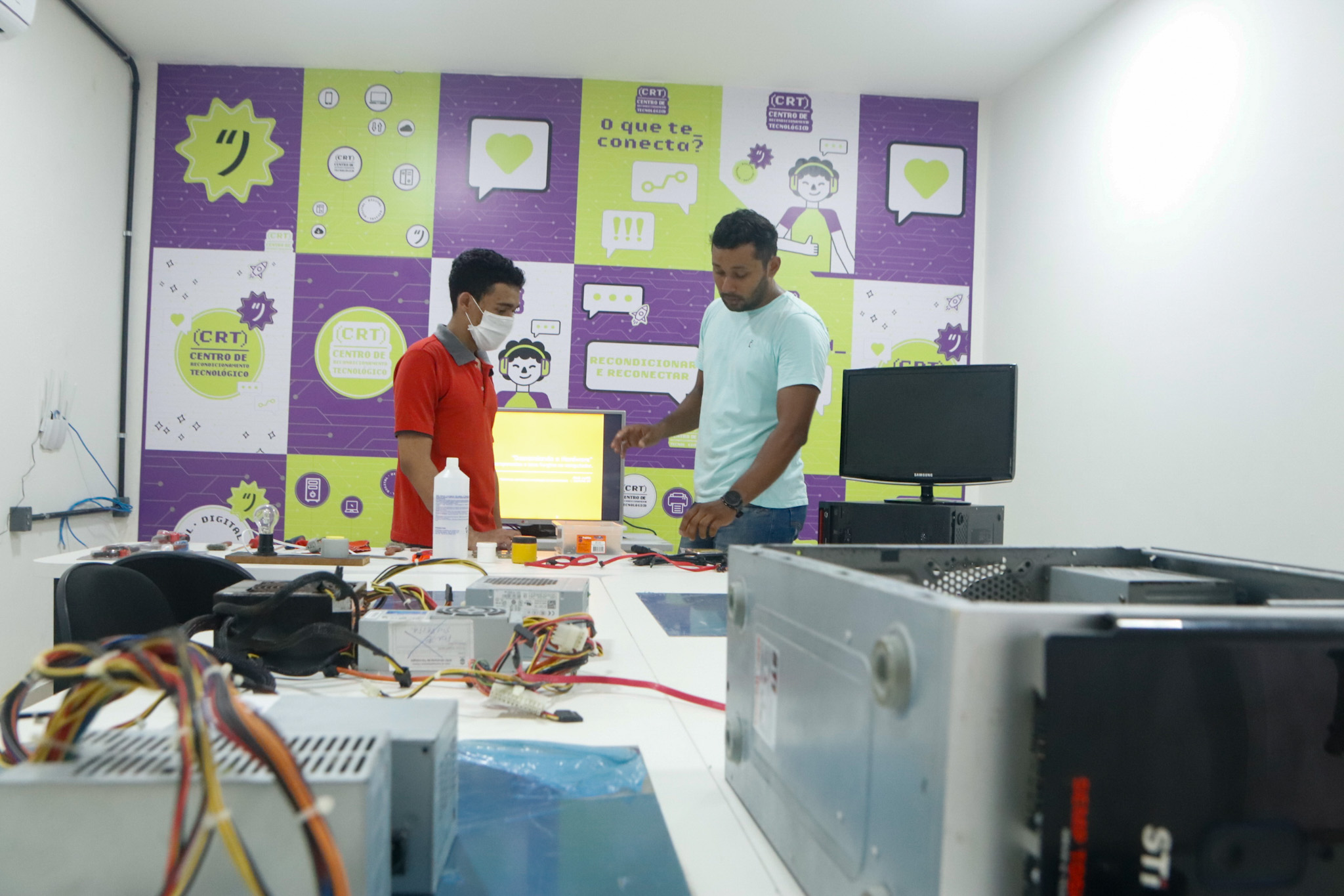 Sala de aula mostra aluno e professor além de computadores abertos