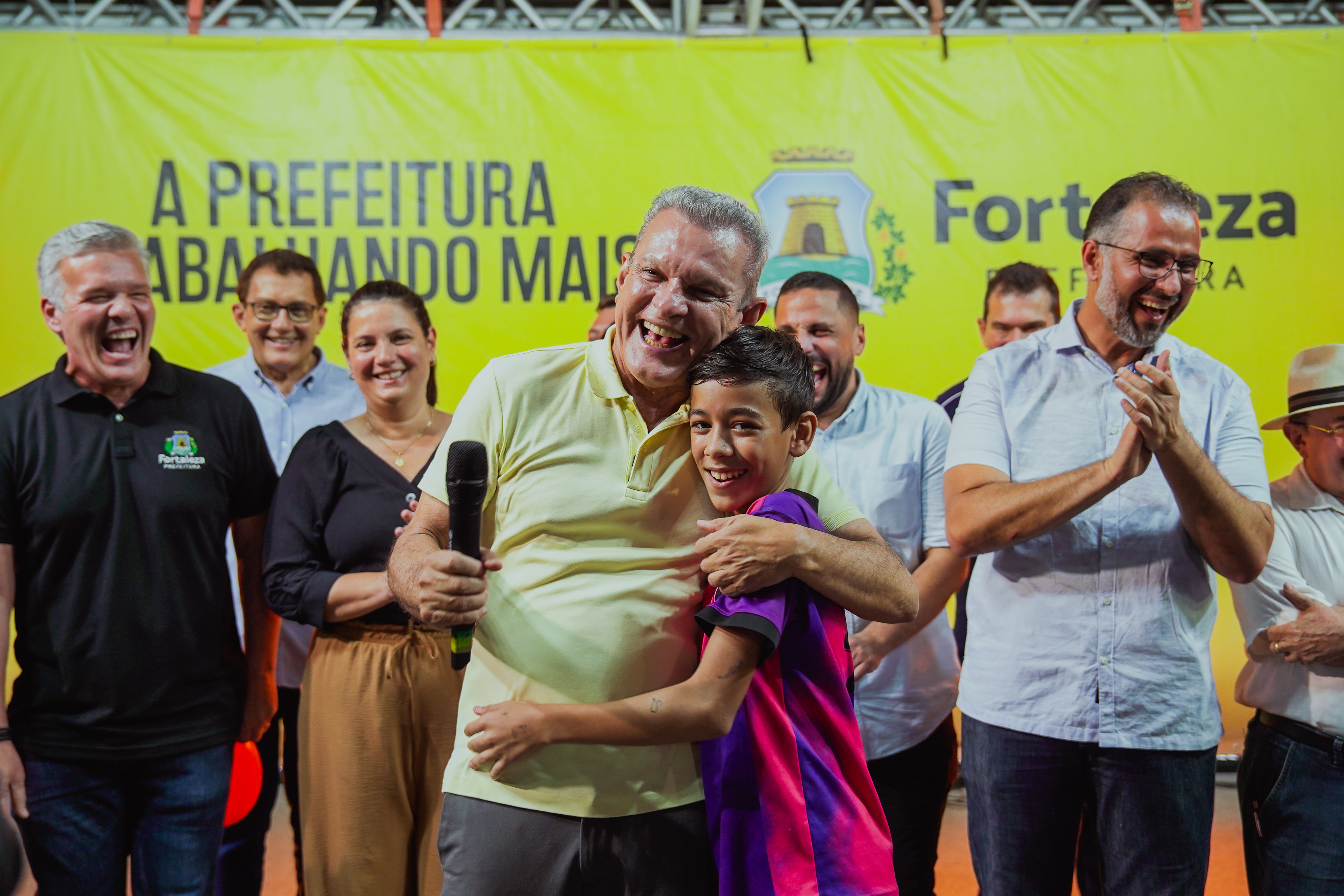 prefeito abraçando criança no palco