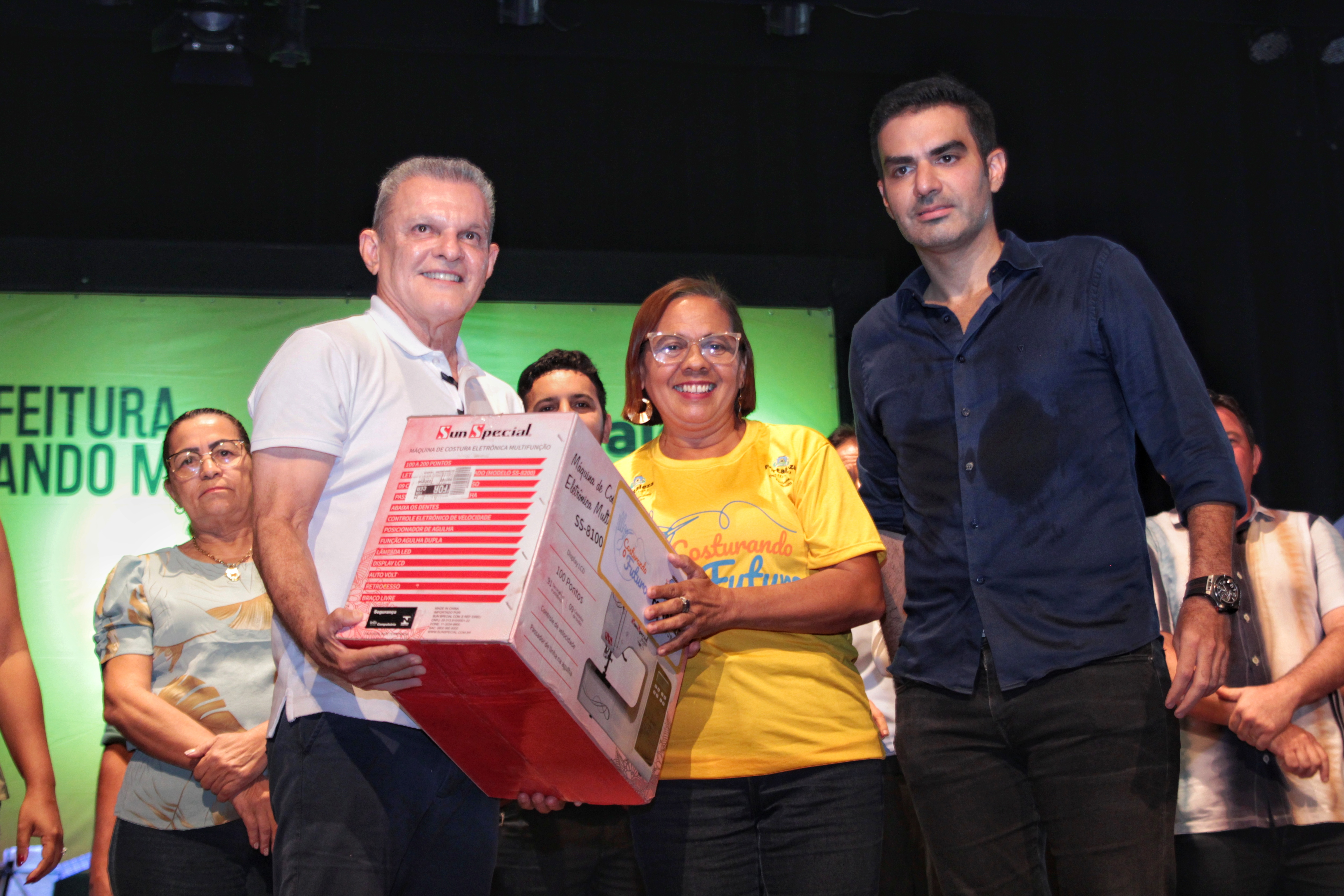 prefeito e secretario entregando maquina de costura a costureira