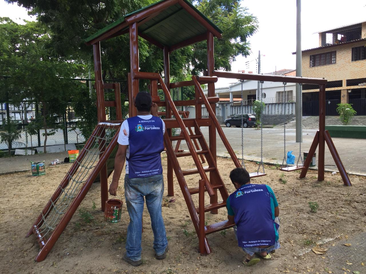 Equipe de manutenção realizando reparo em parquinho infantil 